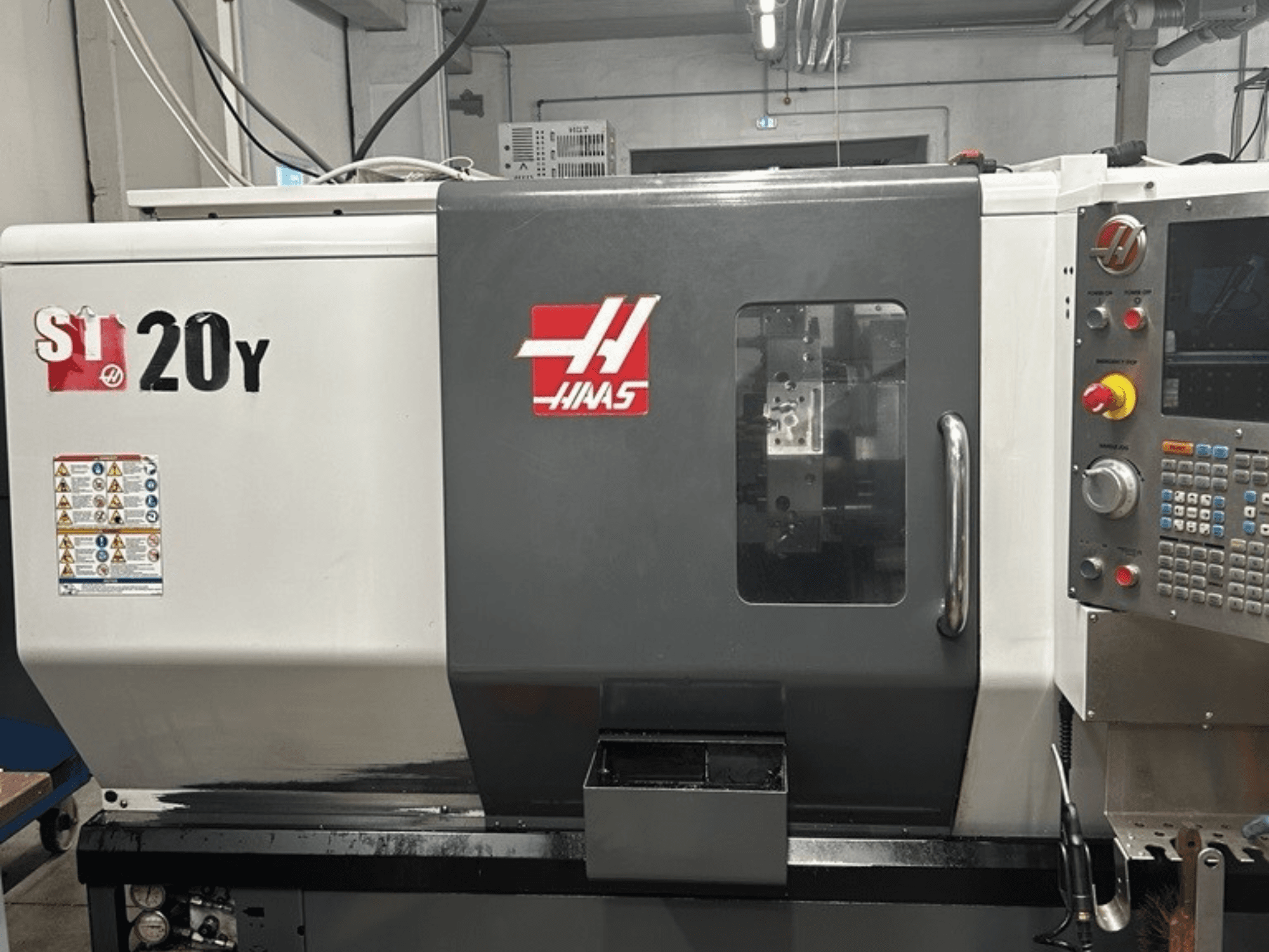 Токарный станок с ЧПУ Haas ST-20Y, вид спереди, панель управления, наклейки безопасности и рабочее окно.