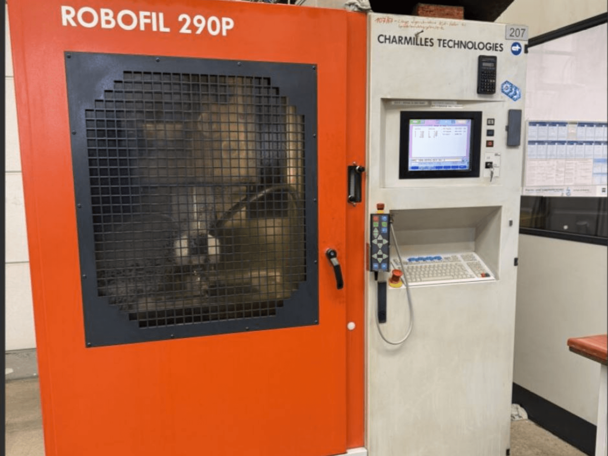 Вид спереди на проволочно-вырезной станок CHARMILLES TECHNOLOGIES Robofil 290P с панелью управления и огражденной сеткой рабочей зоной.
