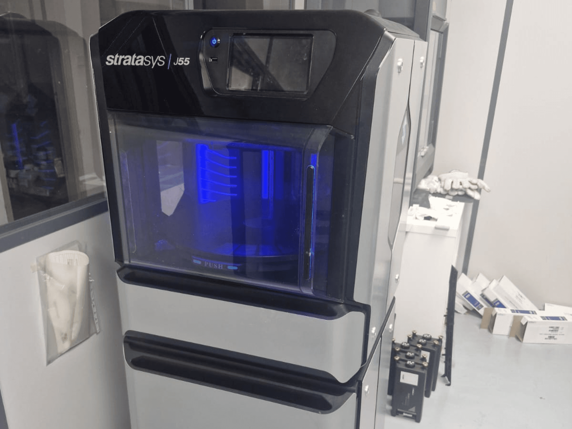 Пластиковый 3D-принтер Stratasys J55 Prime вид сбоку, демонстрирующий его элегантный дизайн и подсвеченную область печати.