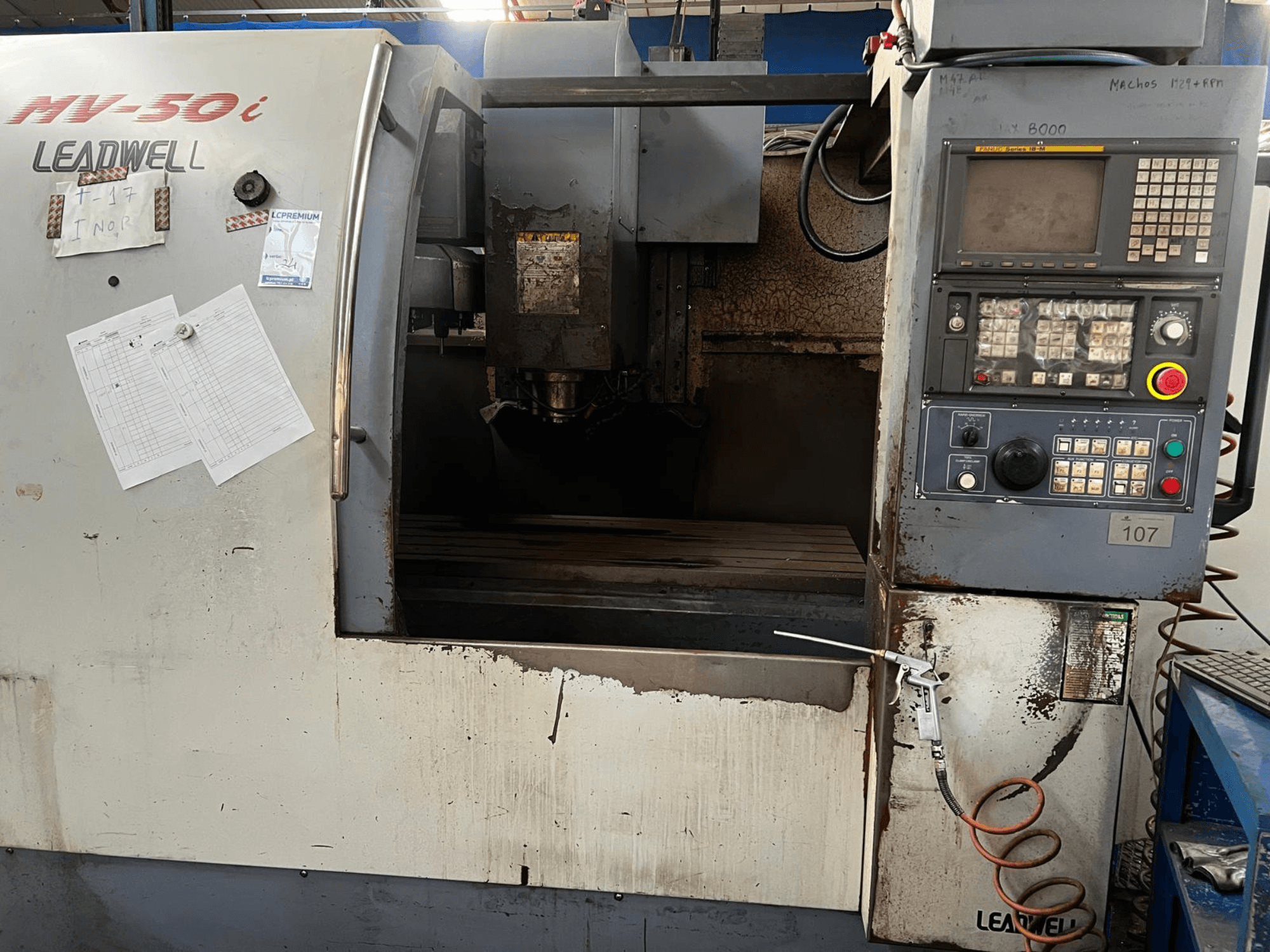 Вертикальный обрабатывающий центр Leadwell MV-50i, вид спереди, на котором видны панель управления, зона шпинделя и рабочий стол с следами износа.