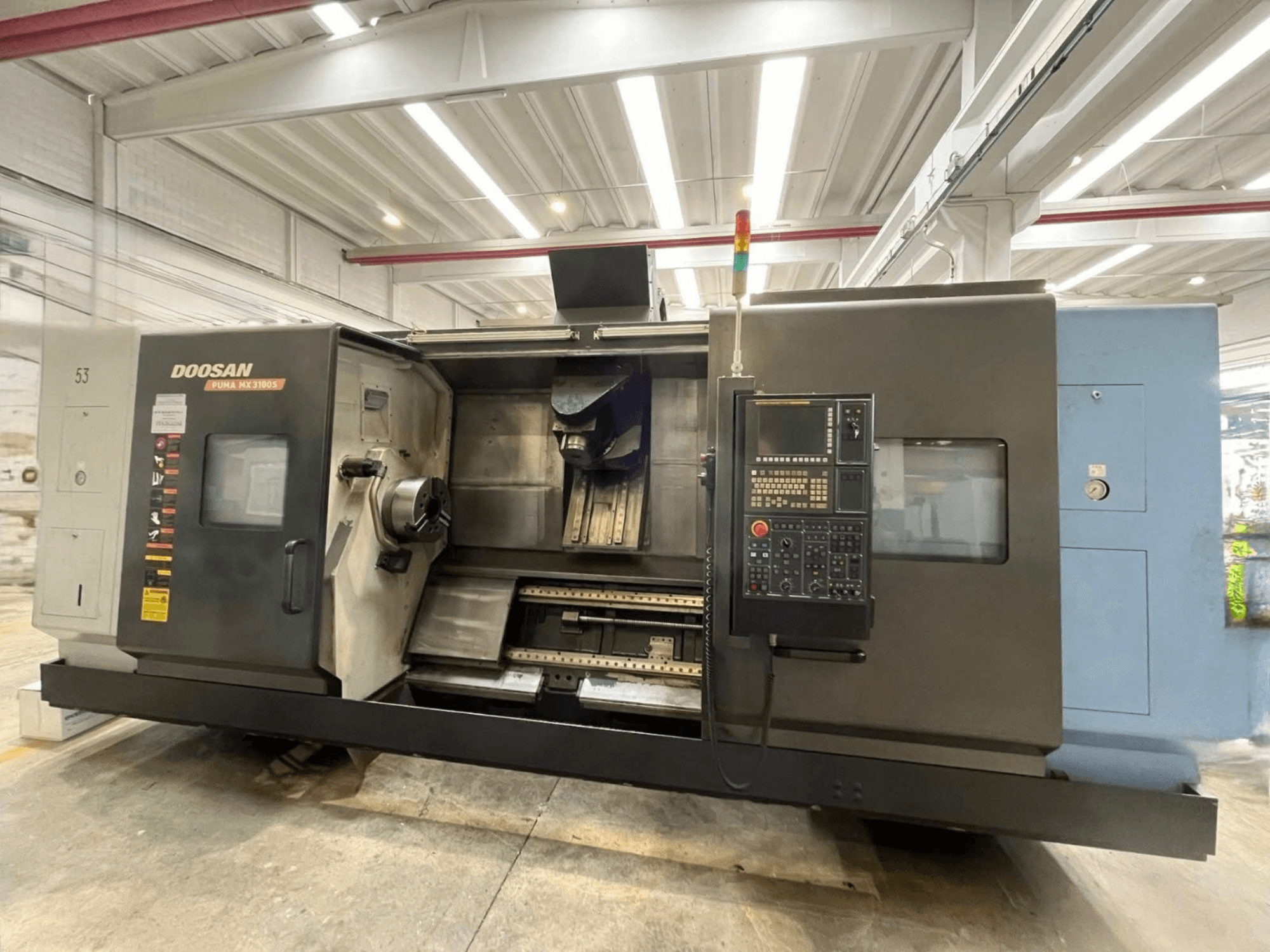 Вид спереди на горизонтально-токарный станок DOOSAN PUMA MX3100 с панелью управления и видимой зоной шпинделя и держателя инструмента.