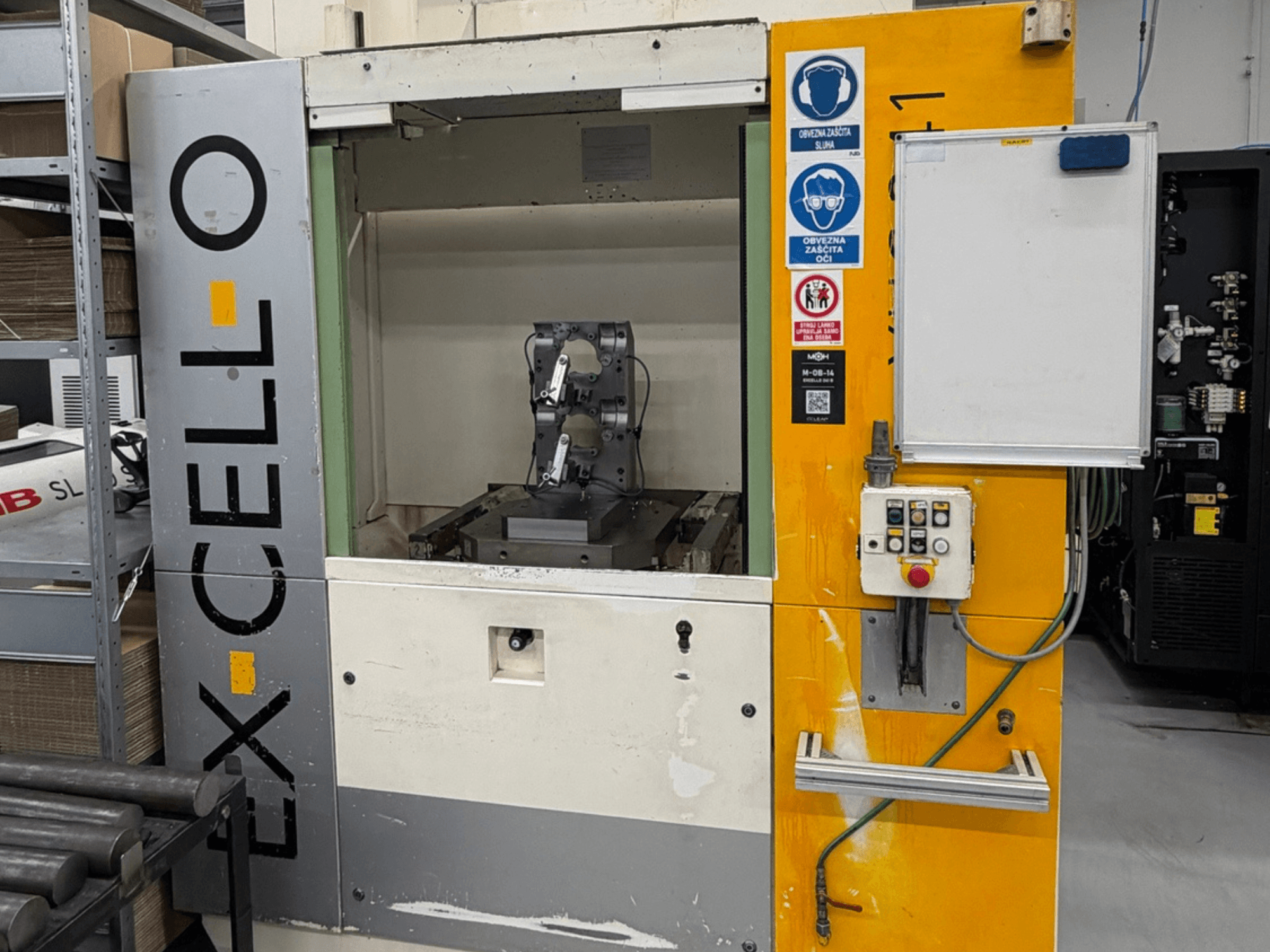 Вид спереди на горизонтальный обрабатывающий центр EXCELLO XHC 241 M/3 с видимой панелью управления и внутренним устройством станка.