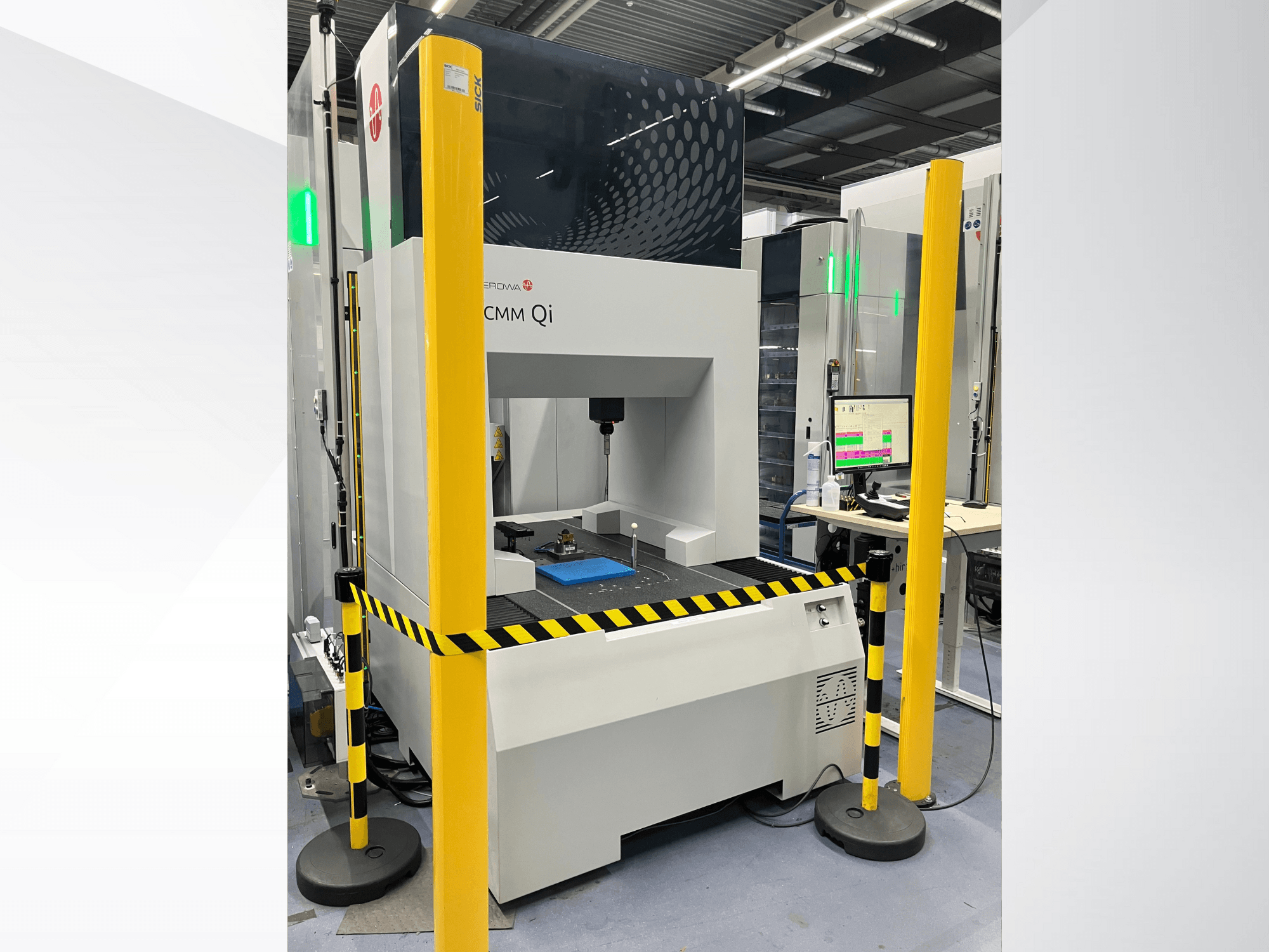 Координатно-измерительная машина CMM Qi компании Aerovent, вид спереди с защитными барьерами и монитором, на котором отображаются данные измерений.