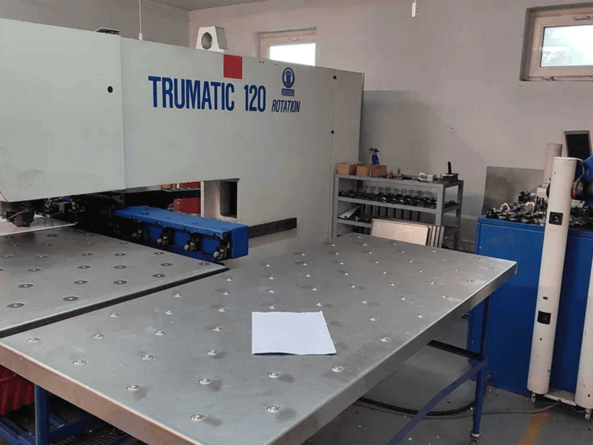 Пробивной станок с ЧПУ TRUMPF TRUMATIC 120R, вид спереди, металлический стол с пробитыми отверстиями и чистый лист.
