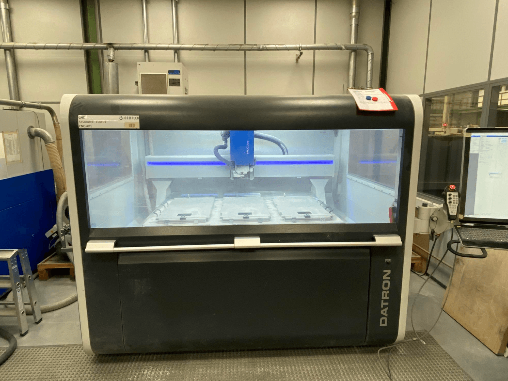 Вертикальный обрабатывающий центр Datron MLCube B, вид спереди, демонстрирует внутреннюю часть станка и панель управления.