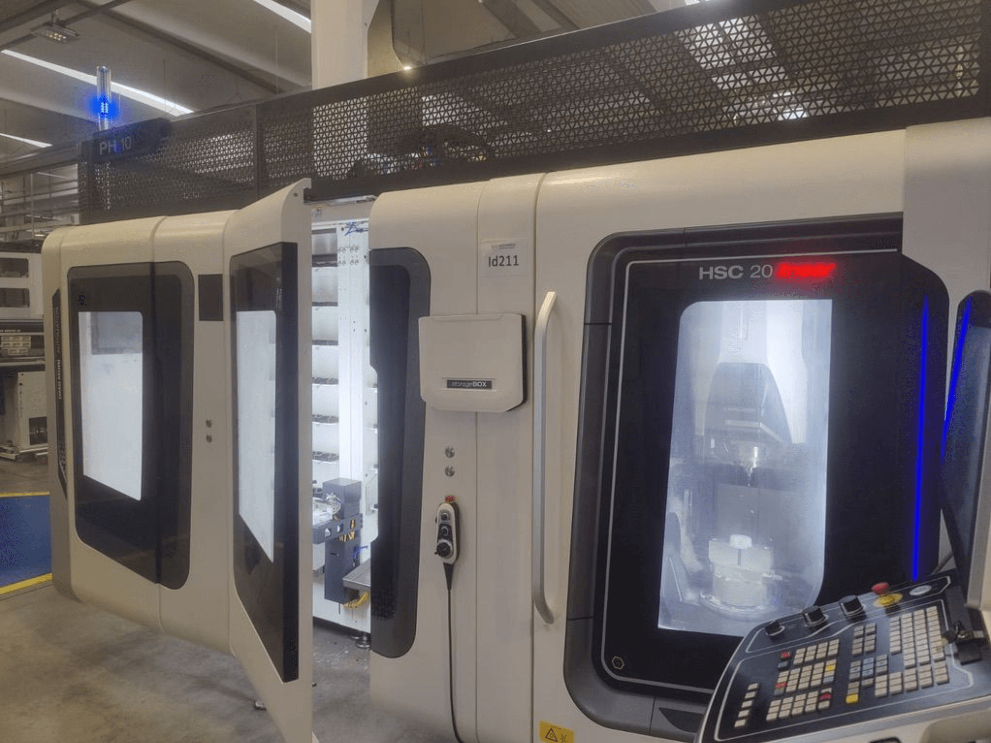 Вертикальный обрабатывающий центр DMG MORI HSC 20, вид спереди, видны открытые двери, открывающие внутреннее пространство обрабатывающего центра и панель управления.