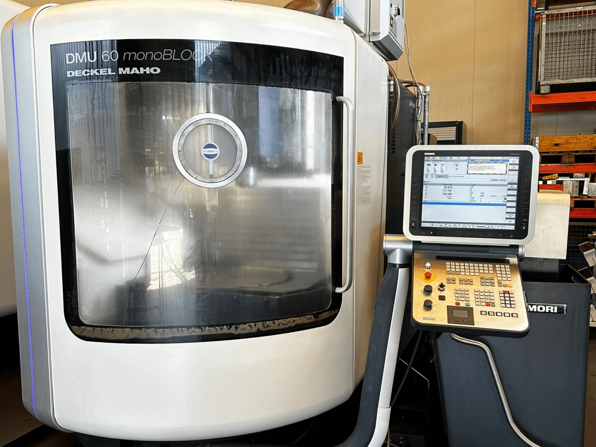 Вертикальный обрабатывающий центр DMG MORI DMU 60 monoBLOCK, вид спереди, показывает панель управления с сенсорным экраном и отражающее окно.