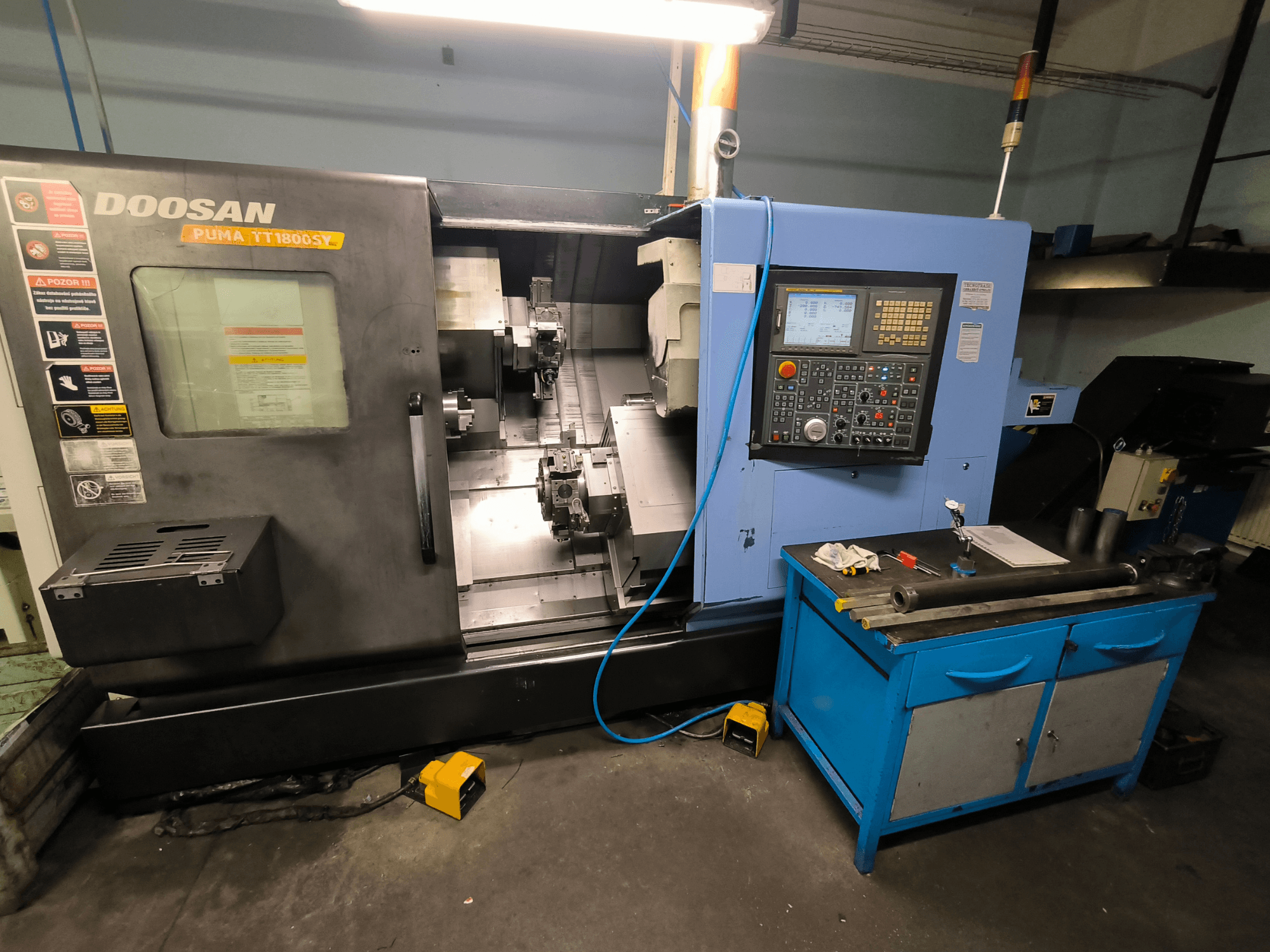 Токарный станок с ЧПУ Doosan Puma TT1800SY, вид спереди, демонстрирует панель управления, рабочую зону с инструментами и компоненты станка.