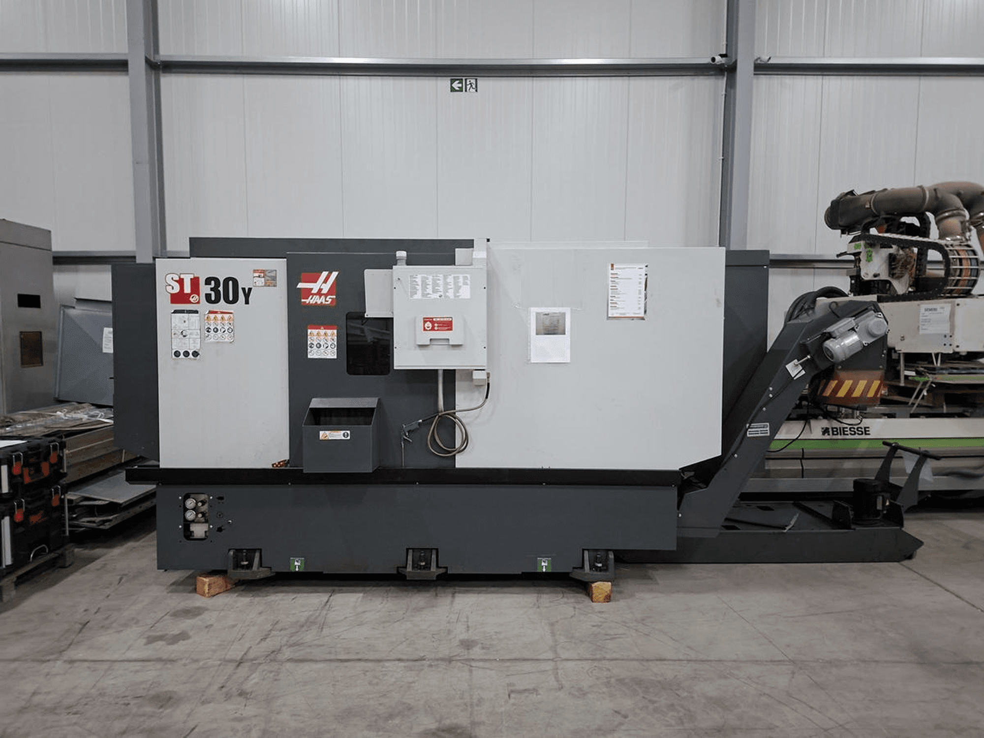 Горизонтальный токарный станок Haas ST-30Y в боковом ракурсе: на фотографии видны органы управления, маркировка и прочная конструкция станка в просторном цехе.