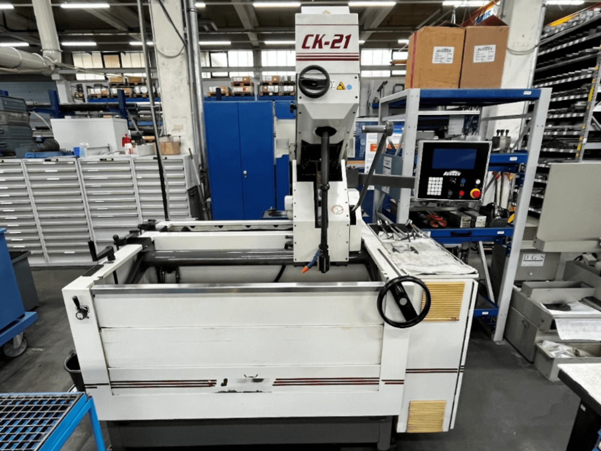 Вертикальный хонинговальный станок Sunnen CK-21-CC на переднем плане, на заднем плане - органы управления, зона хонингования и вспомогательное оборудование.