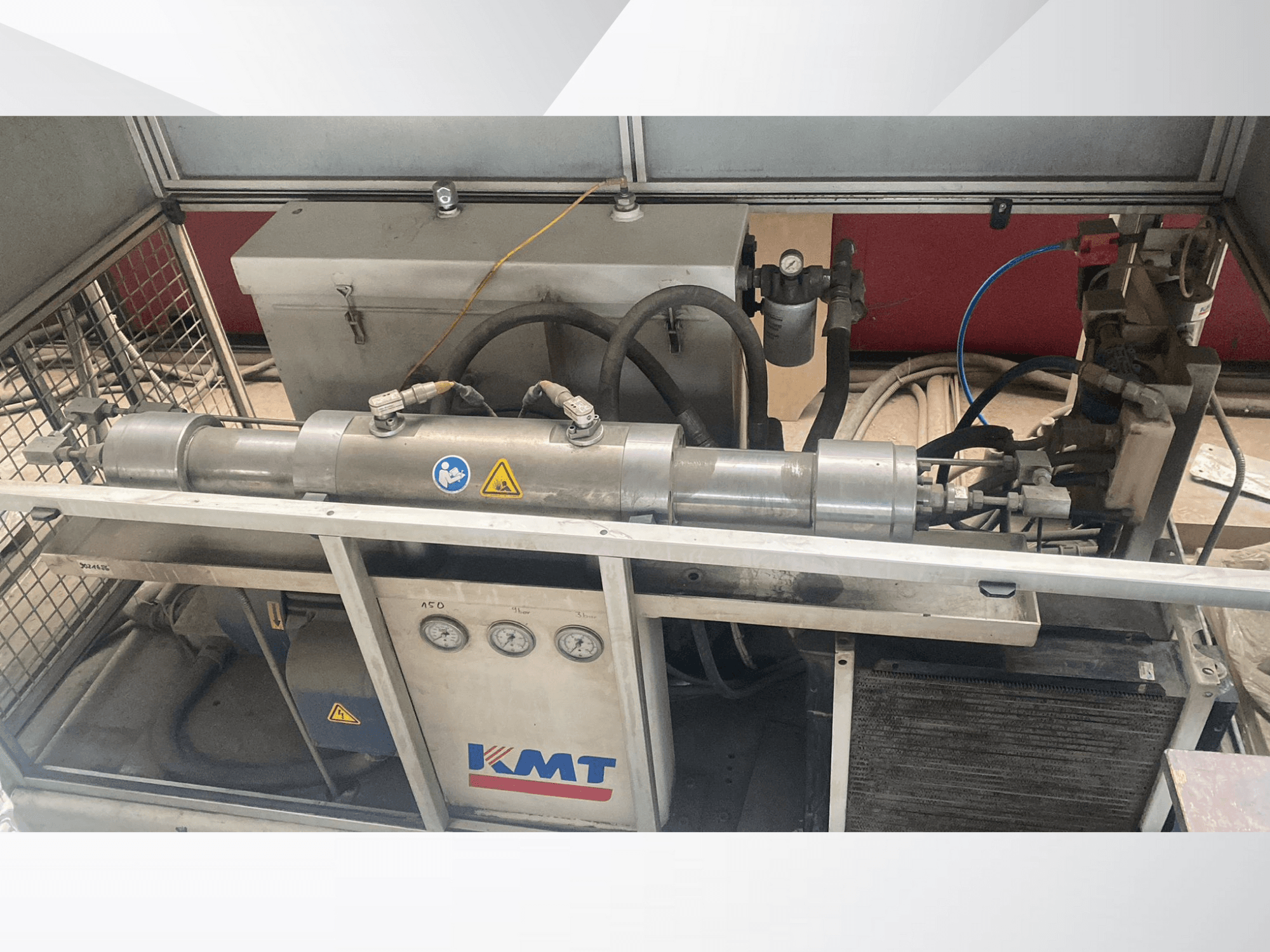 Гидравлическая машина KMT с видом спереди, с манометрами, шлангами и металлическим корпусом, идеально подходит для промышленного применения.