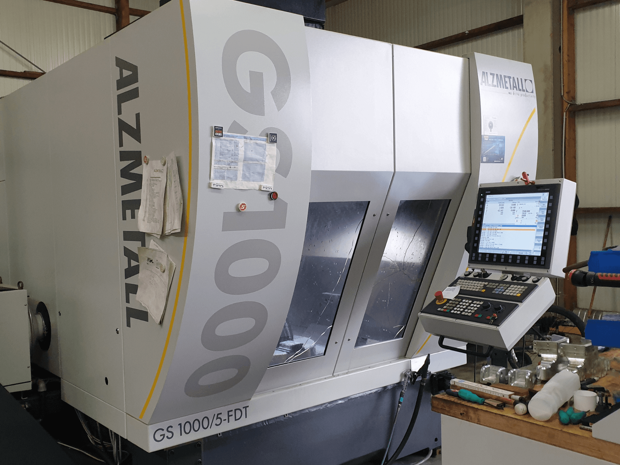 Вертикальный обрабатывающий центр Alzmetall GS 1000/5-FDT в виде спереди, на котором видны панель управления и рабочая зона.