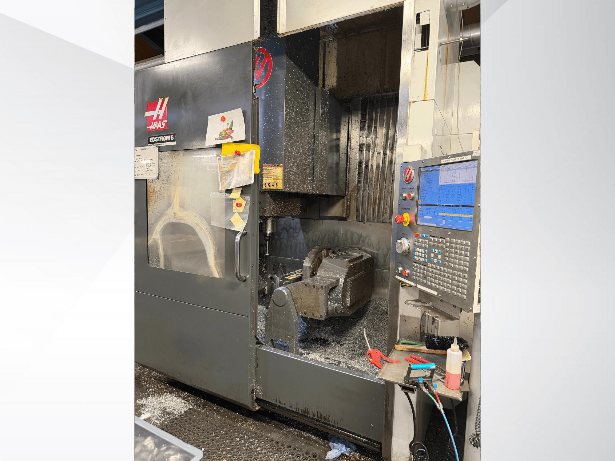 Станок с ЧПУ Haas модели EDSTROM S, вид спереди, демонстрирующий металлическую заготовку, панель управления и металлическую стружку внутри.