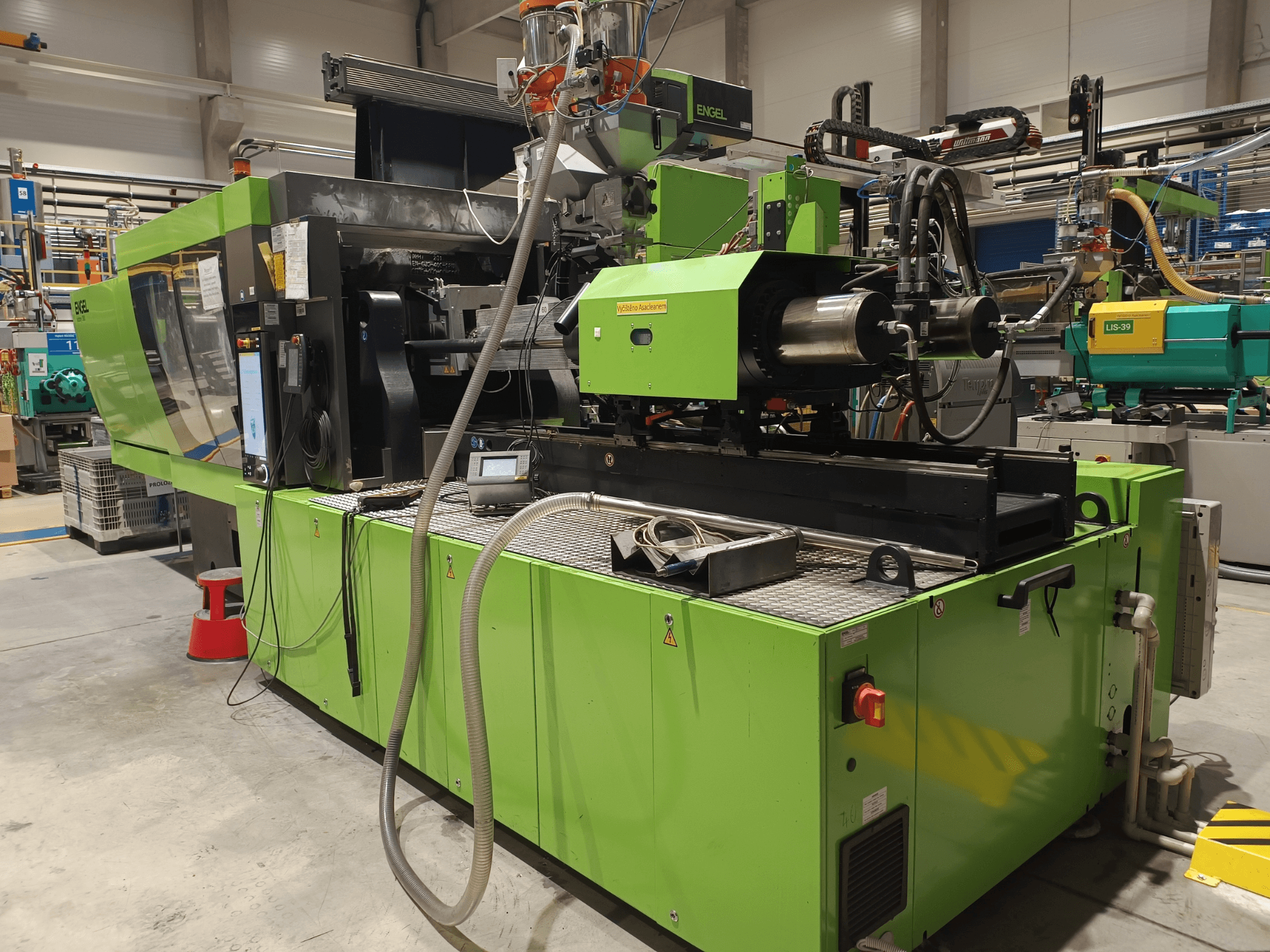 Термопластавтомат Engel, вид сбоку, зеленый внешний вид, видна панель с сенсорным экраном и гидравлические компоненты.