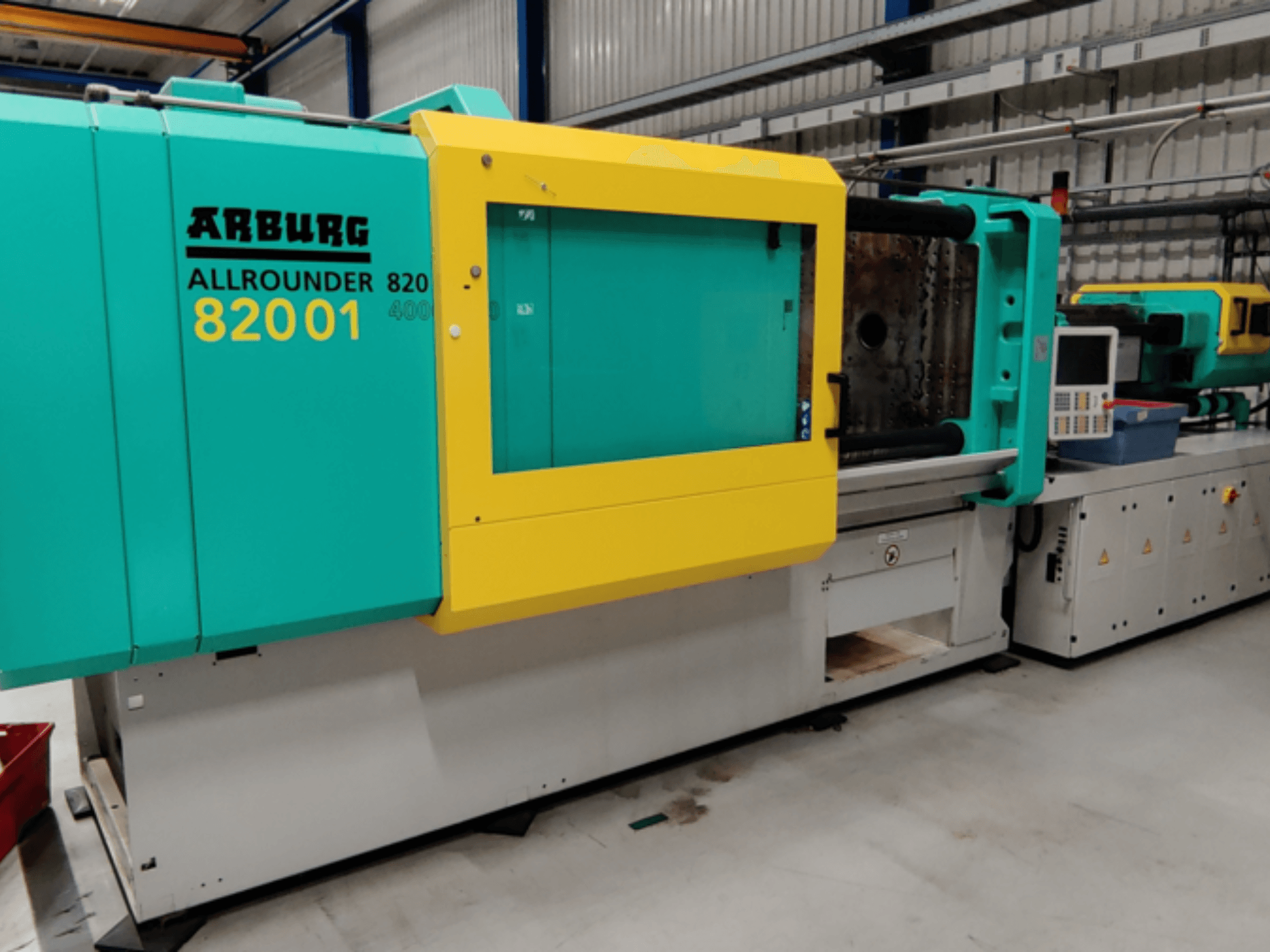 Термопластавтомат Arburg ALLROUNDER 82001 в желто-зеленом цвете, вид сбоку, демонстрирующий панель управления и рабочие функции.