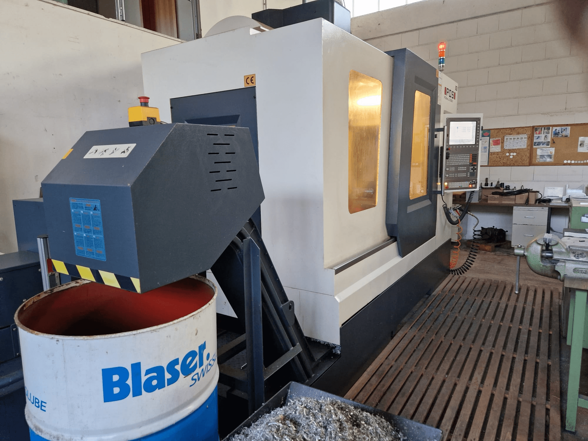 Вид спереди вертикального обрабатывающего центра POSmill C 1050, видна система охлаждения над барабаном Blaser и панель управления.