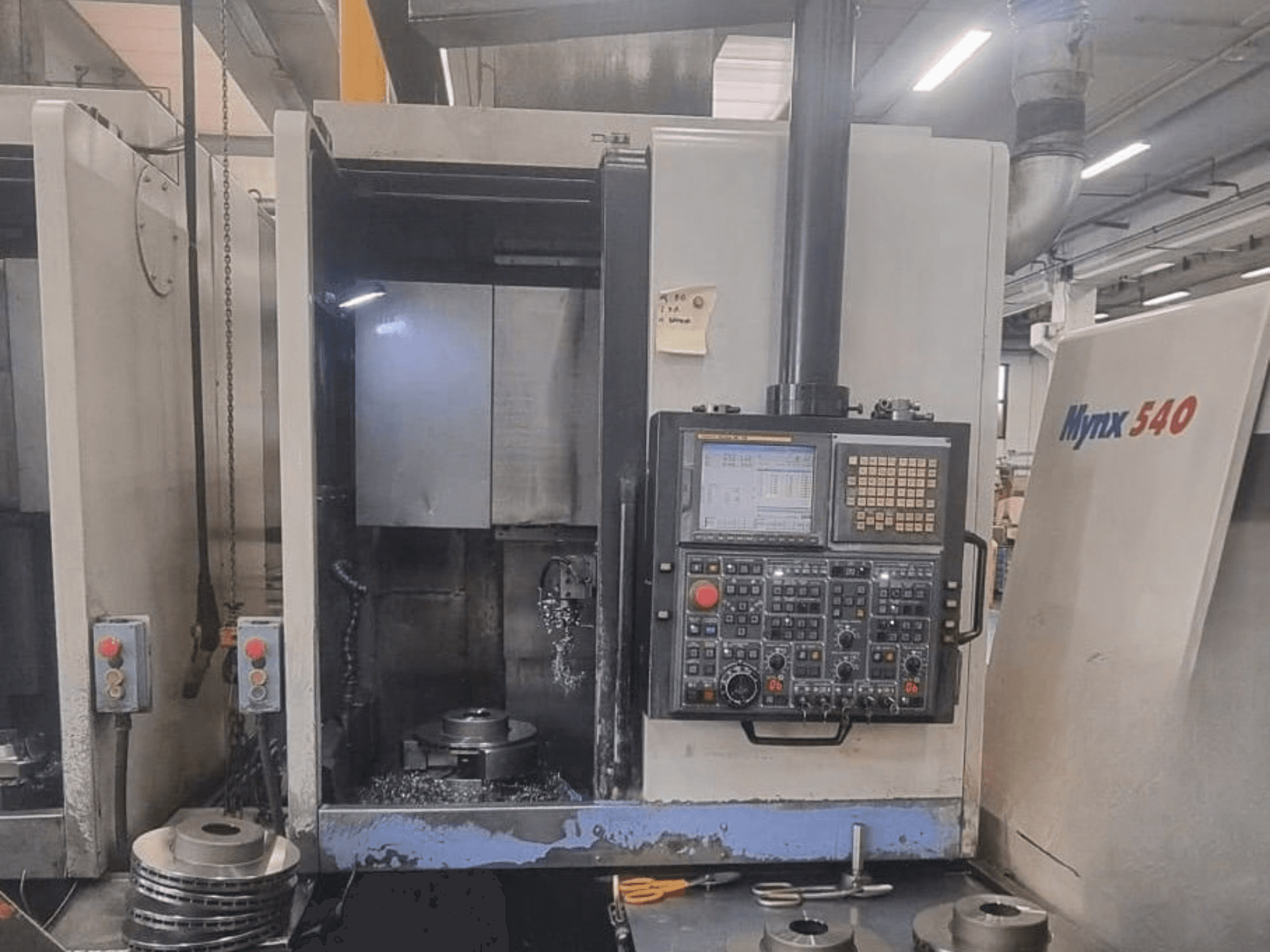 Вид спереди вертикального токарного станка DOOSAN PUMA V400-2SP с панелью управления и заготовкой, установленной внутри станка.