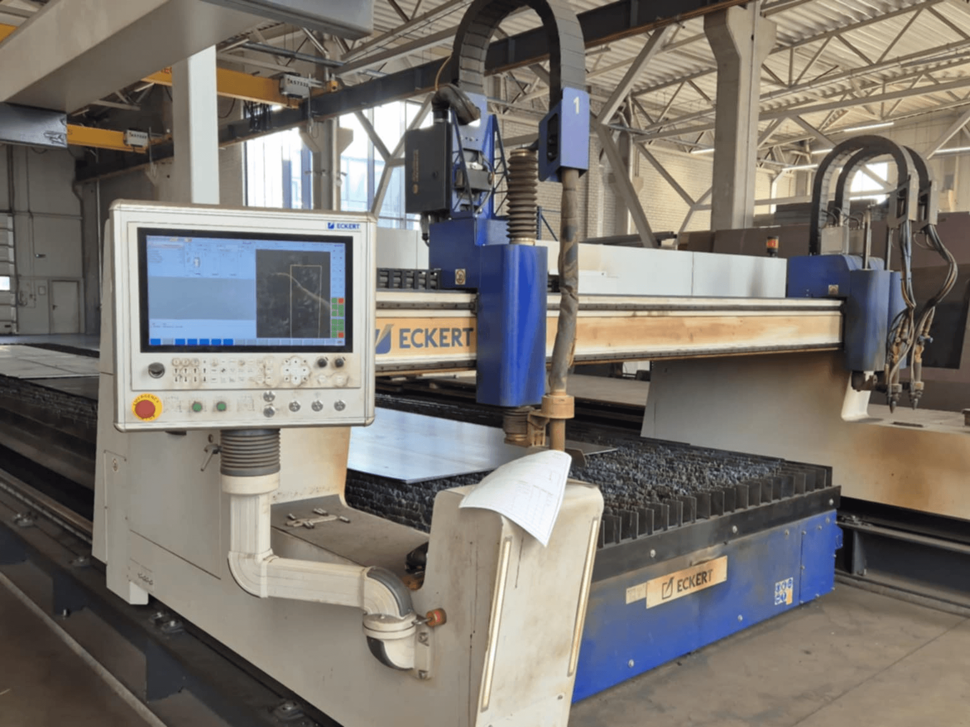 Панель управления станка с ЧПУ ECKERT с видом спереди, с сенсорным дисплеем и различными кнопками управления.