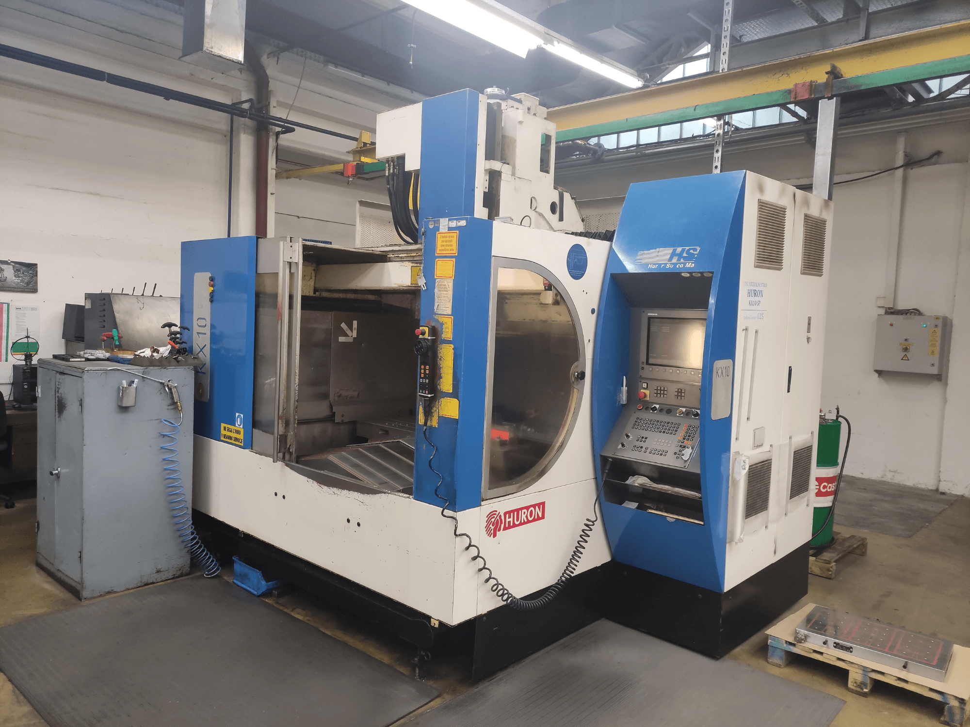 Станок с ЧПУ HURON KX10 в мастерской, вид спереди, с панелью управления и большим отверстием для обработки.