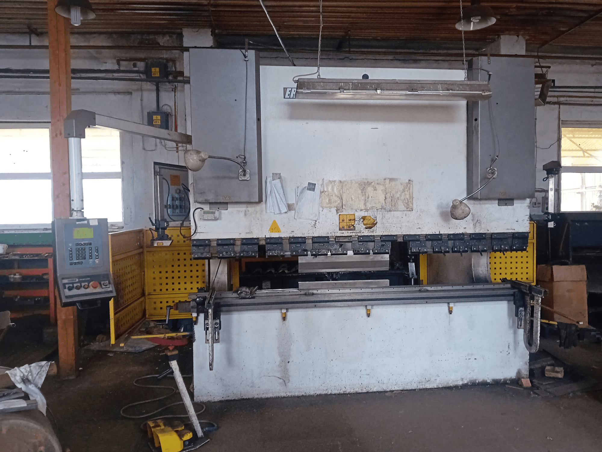 Гидравлический пресс ERMAK CNC HAP 3100x300 с панелью управления и верстаком в мастерской, вид спереди.