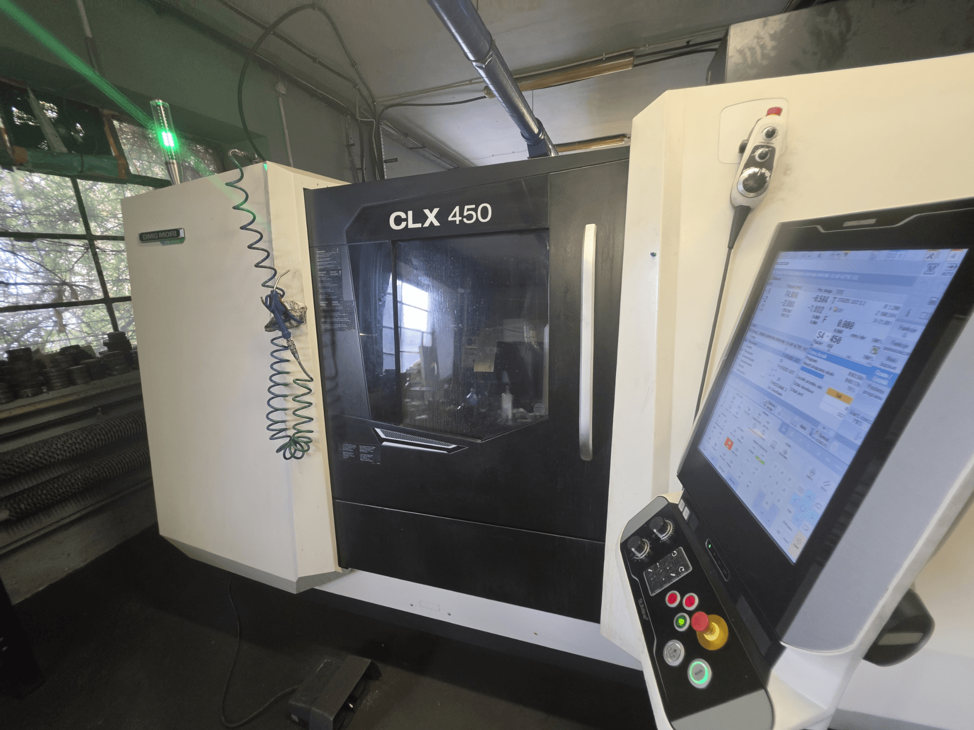 Горизонтальный токарный станок DMG MORI CLX 450 V3, вид спереди с панелью управления и монитором, на котором отображаются рабочие данные.