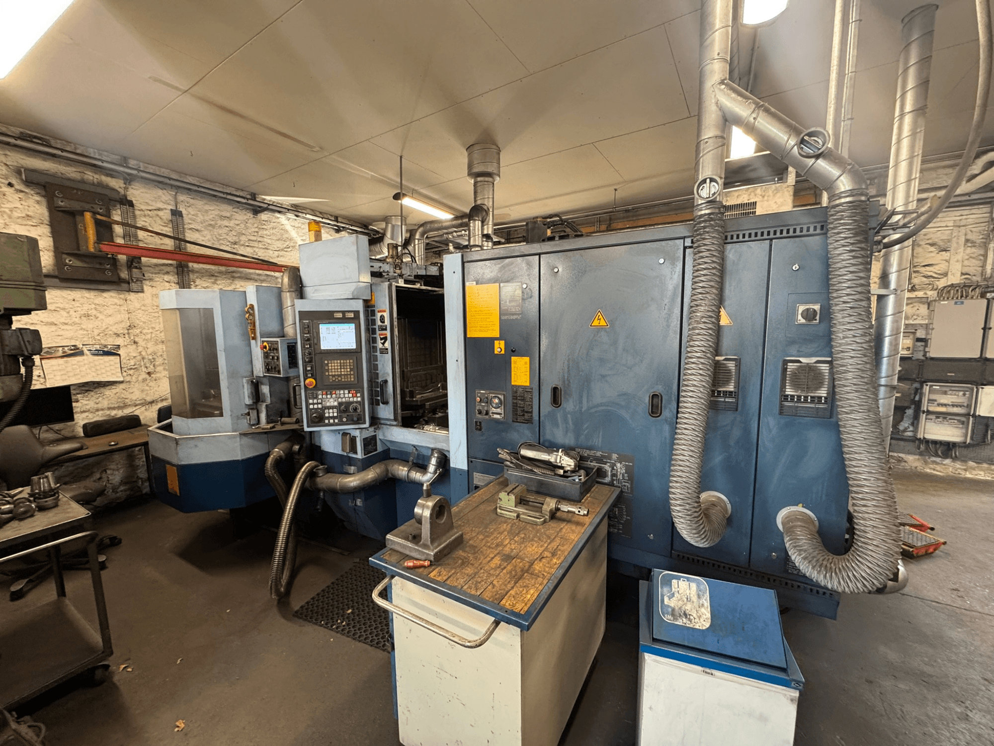 Горизонтальный обрабатывающий центр Matsuura H.PLUS-300 в цехе, вид спереди, на котором видны панель управления и рабочий стол.