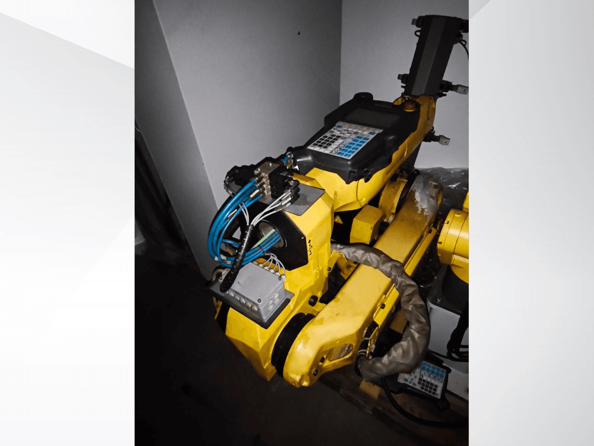 Рука робота FANUC M-20iA на виде сбоку, демонстрирует желтый корпус, панель управления и подключенную проводку.