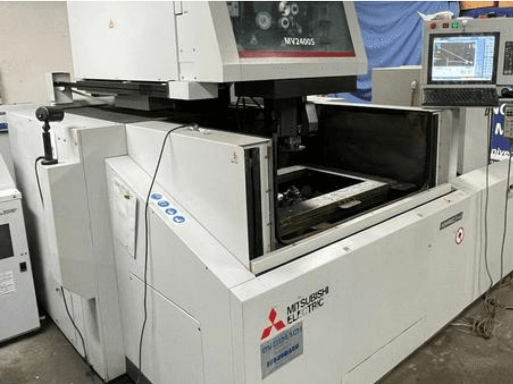 Проволочно-вырезной электроэрозионный станок Mitsubishi Electric MV2400S, вид спереди, показывает панель управления и открытую рабочую зону.