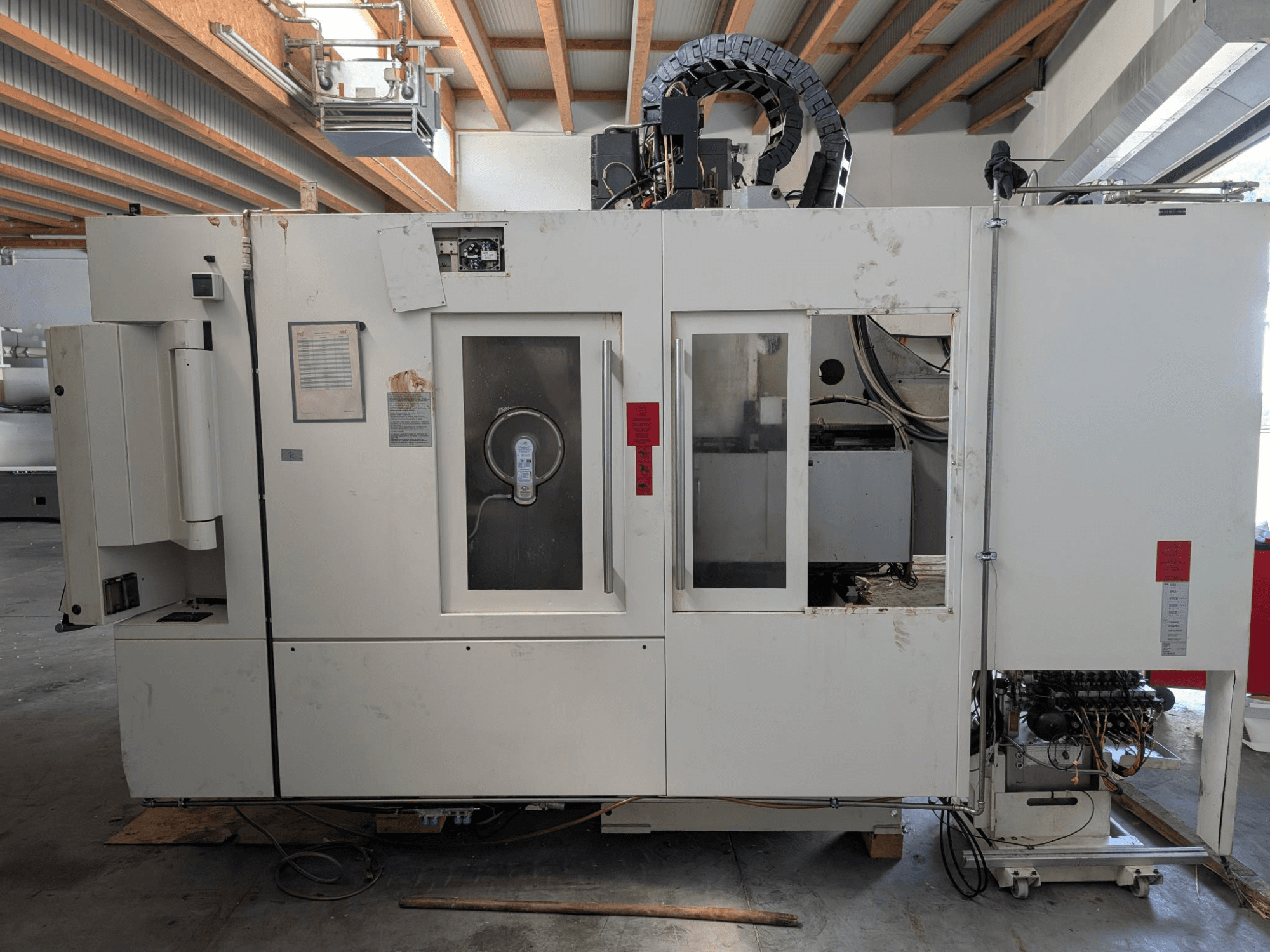 Вертикальный обрабатывающий центр STAMA MC 326, вид сбоку с изображением панели управления, зоны шпинделя и различных надписей на станке.