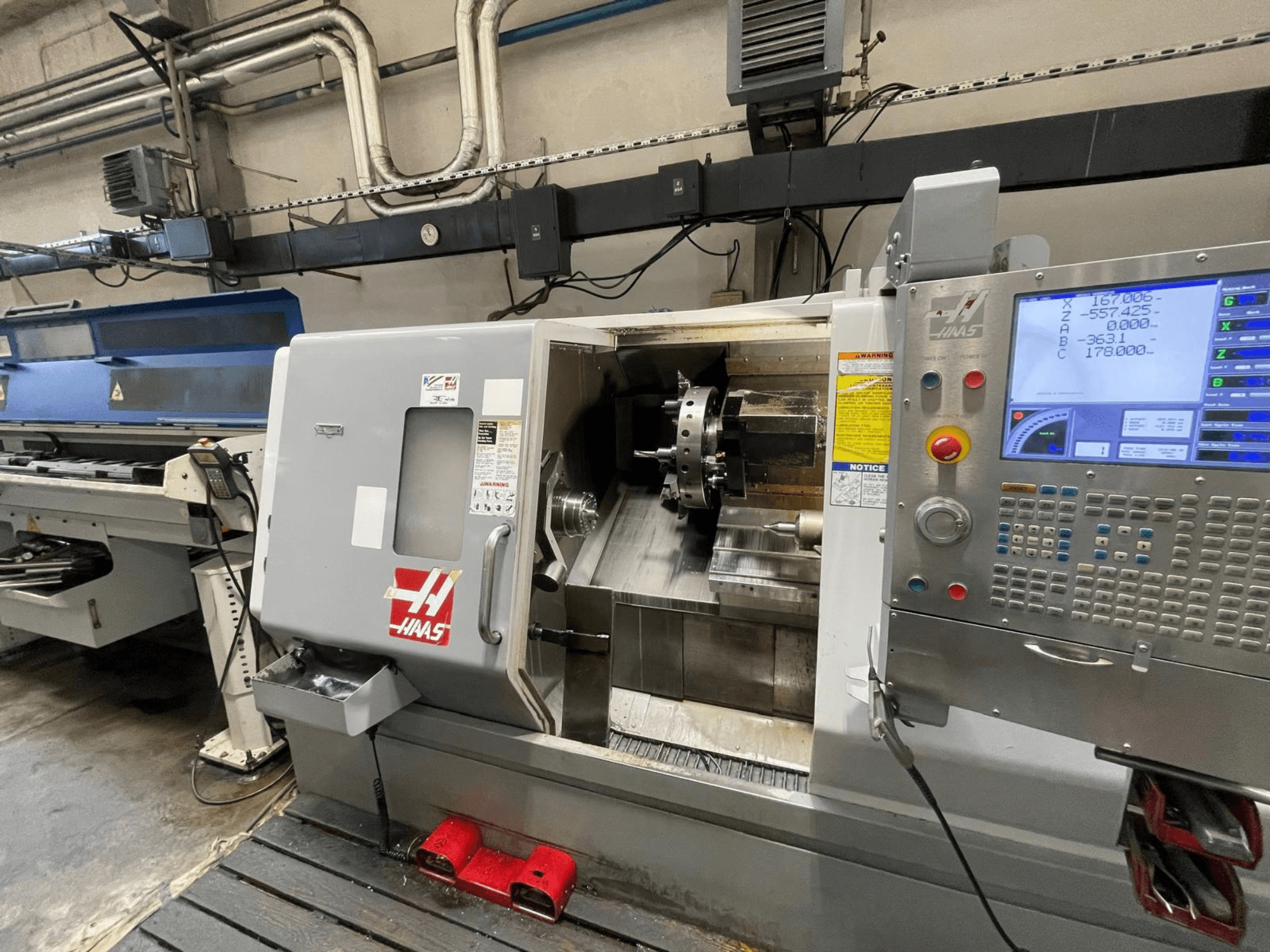 Горизонтальный токарный станок Haas SL-30THE в цехе, оснащенный цифровой панелью управления и открытой рабочей зоной.