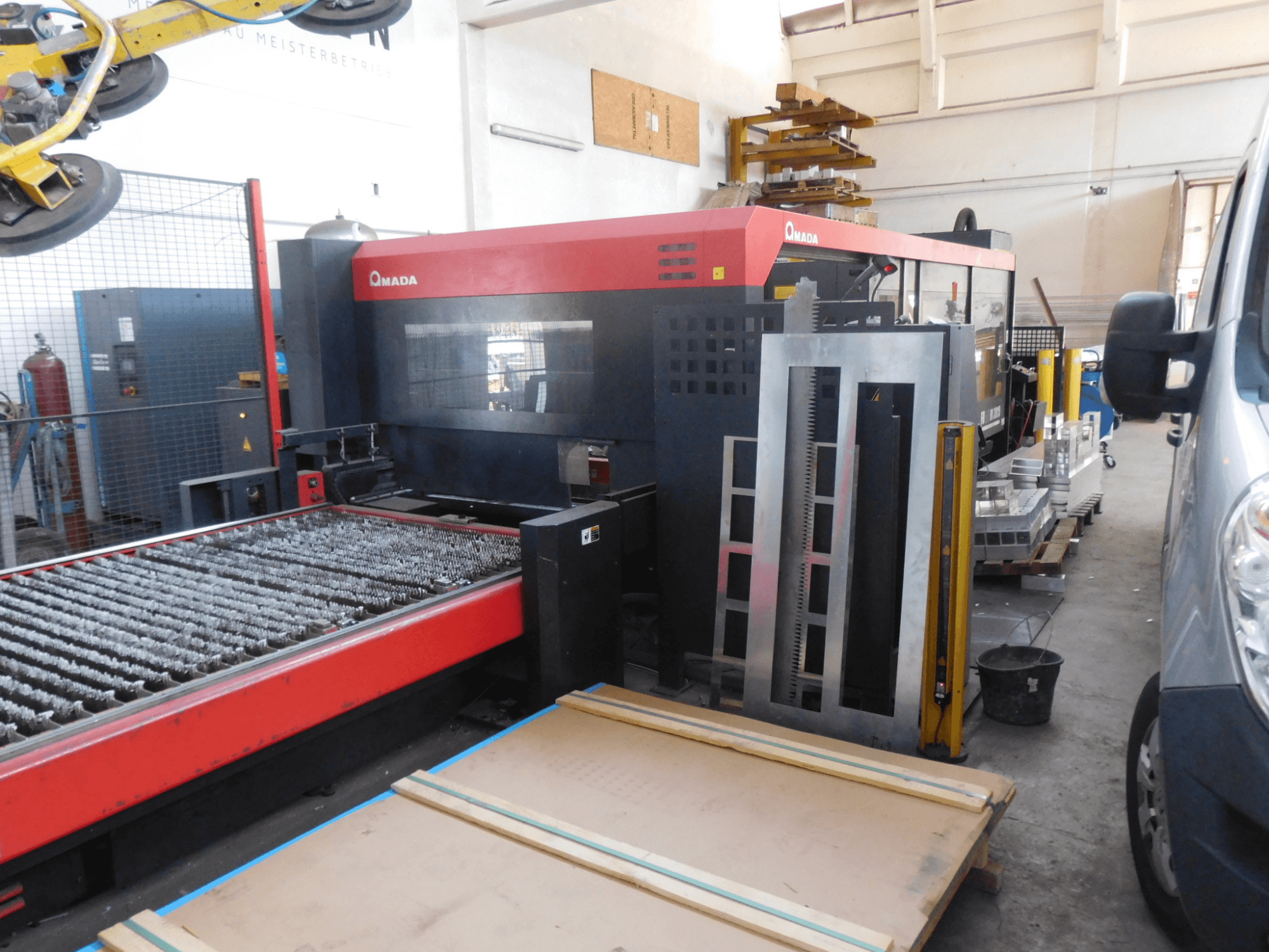 Вид спереди на станок лазерной резки СО2 AMADA FO-3015 II RI, на котором изображена режущая станина и окружающая ее рабочая зона.