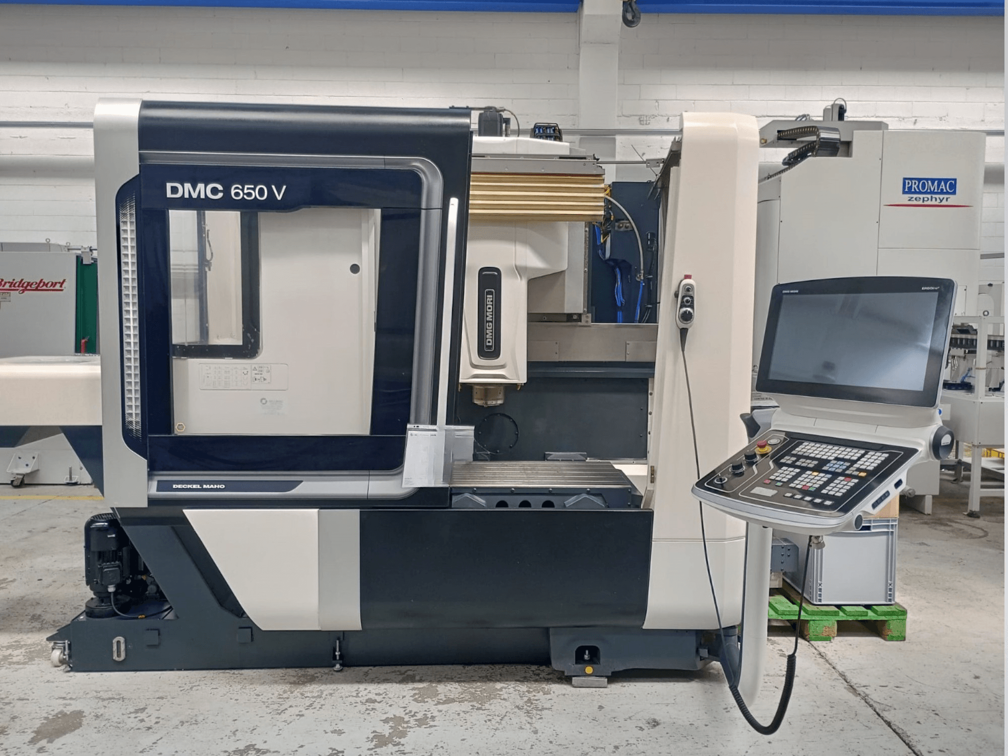 Станок с ЧПУ Decker Maho DMC 650 V вид сбоку, панель управления с кнопками и экраном, в промышленной обстановке.