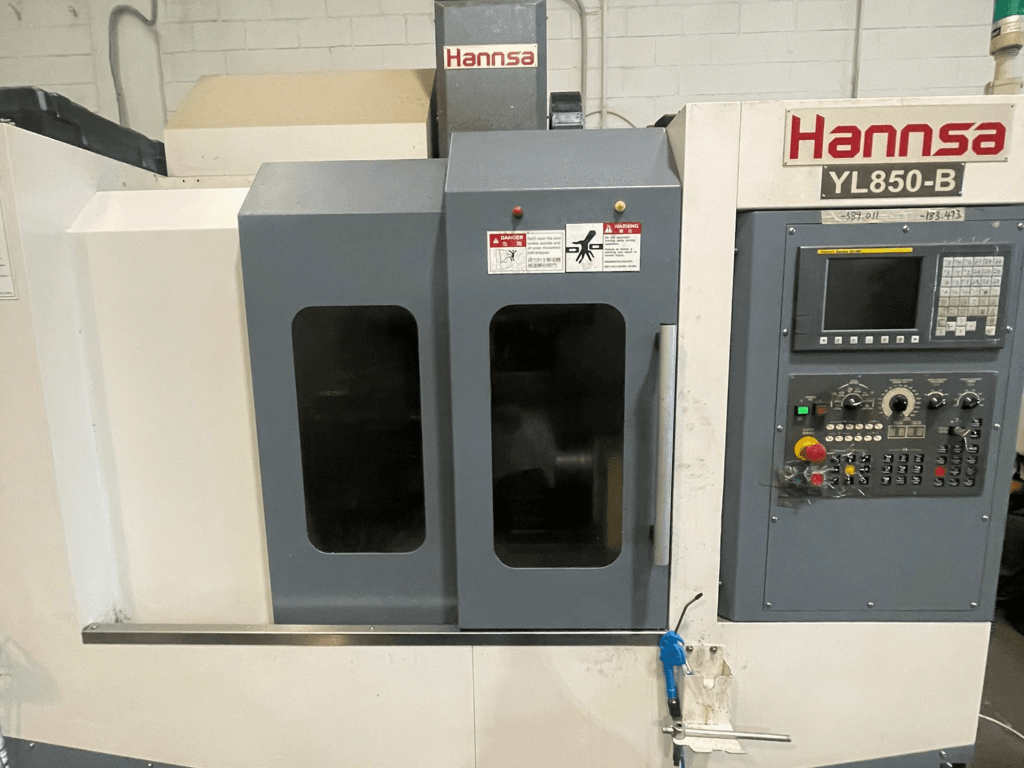 Вертикальный обрабатывающий центр HANNSA YL850-B, вид спереди, панель управления, кнопки управления и два смотровых окна.