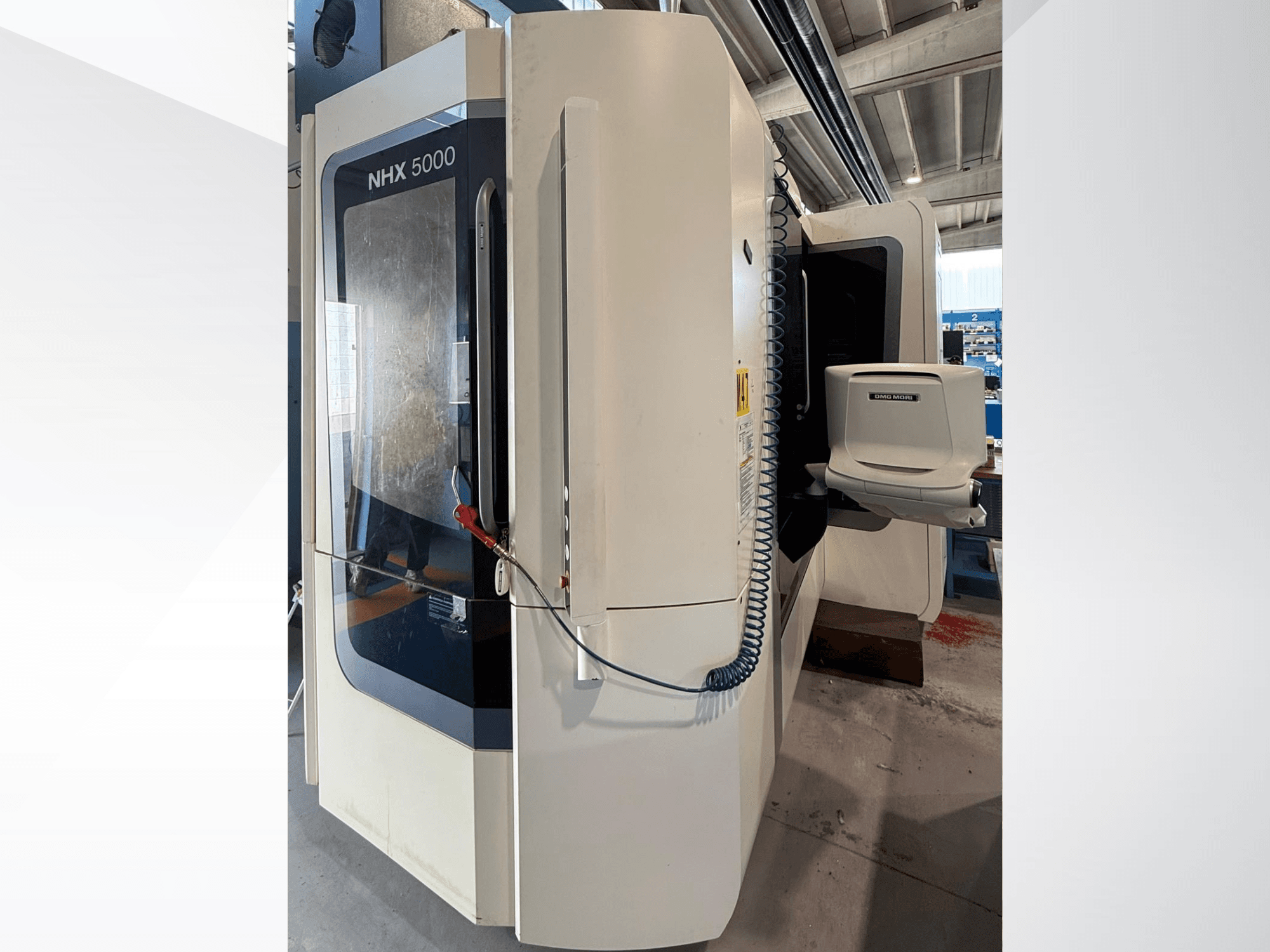 Горизонтальный токарный станок DMG MORI NHX 5000, вид спереди, на котором видны панель управления и держатель шпинделя.