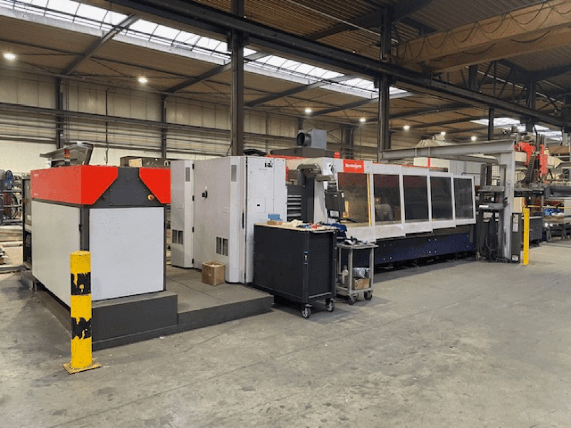 Станок лазерной резки Bystronic BySpeed 3015 CO2, вид сбоку в мастерской, с ярко выраженными красными и серыми элементами дизайна.