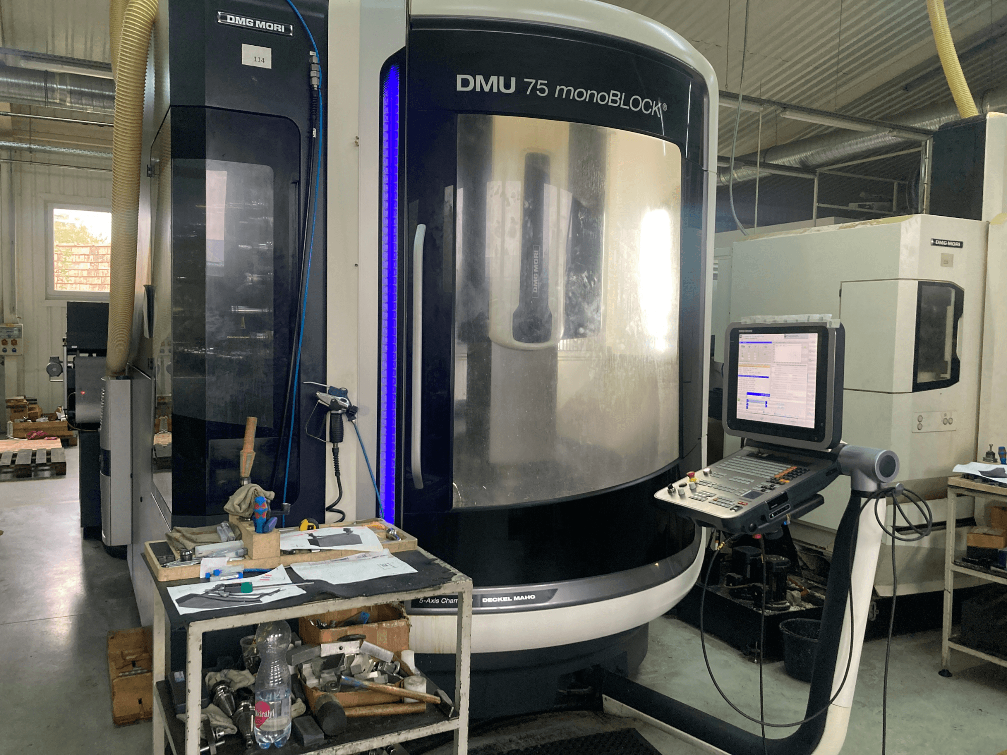 Станок с ЧПУ DMG MORI DMU 75 monoBLOCK®, вид спереди, панель управления, инструменты и рабочая область с материалами.
