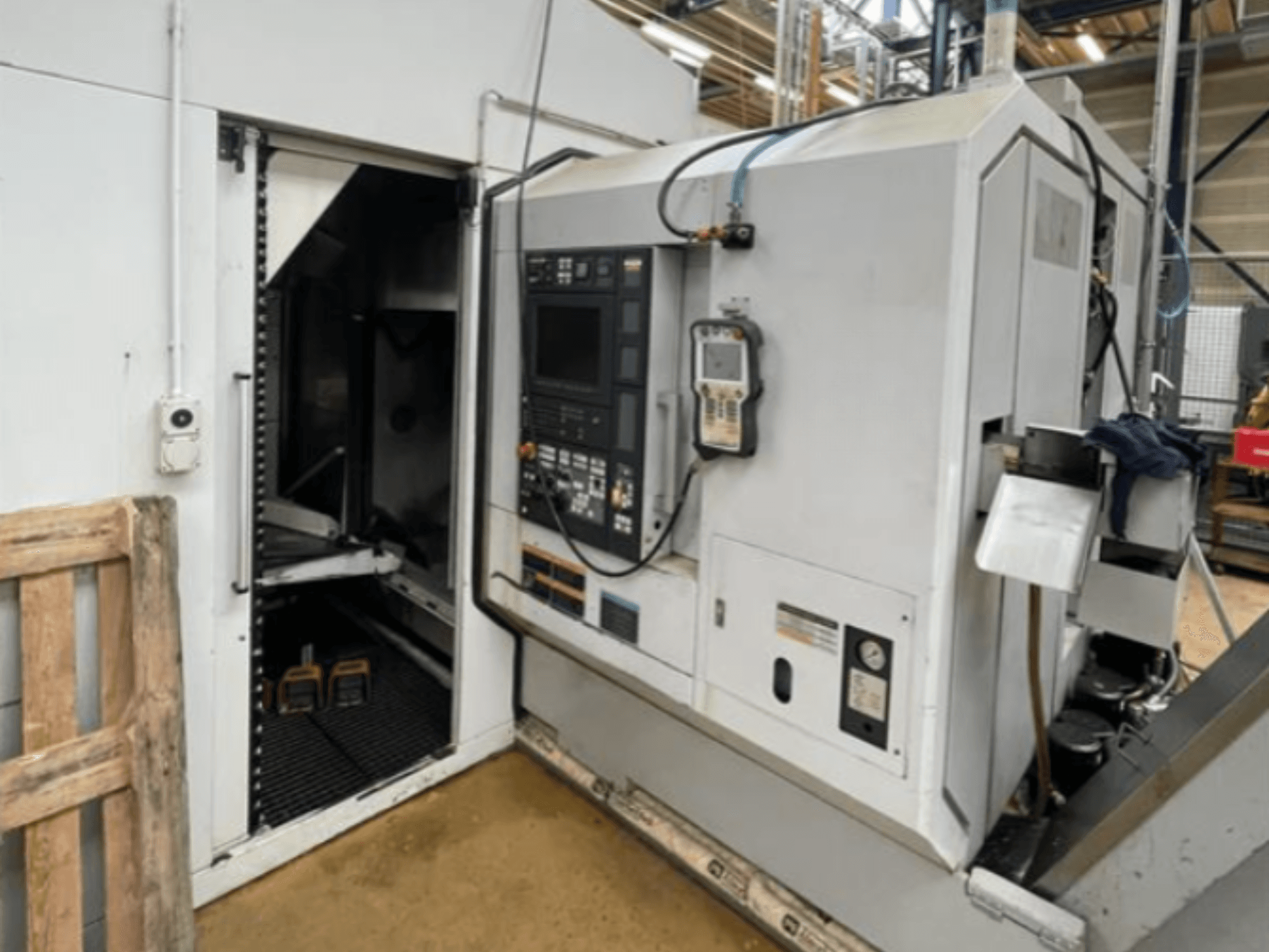 Горизонтальный токарный станок DMG Mori Seiki NZ2000T3Y2, вид сбоку, показывающий панель управления и внутреннюю часть станка.