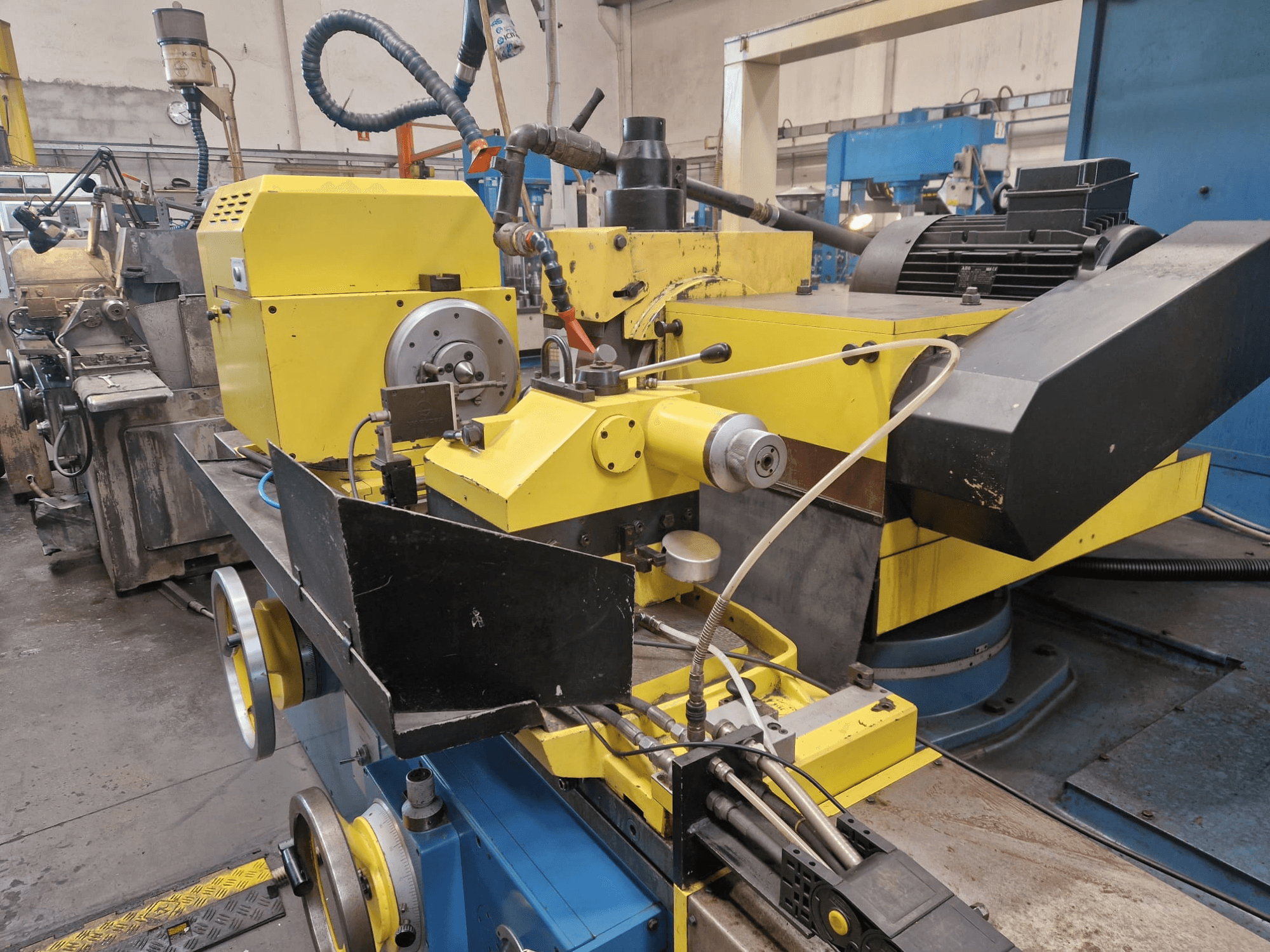 Желтая промышленная машина с черной секцией, на которой изображены циферблат и шланги, вид спереди под небольшим углом.