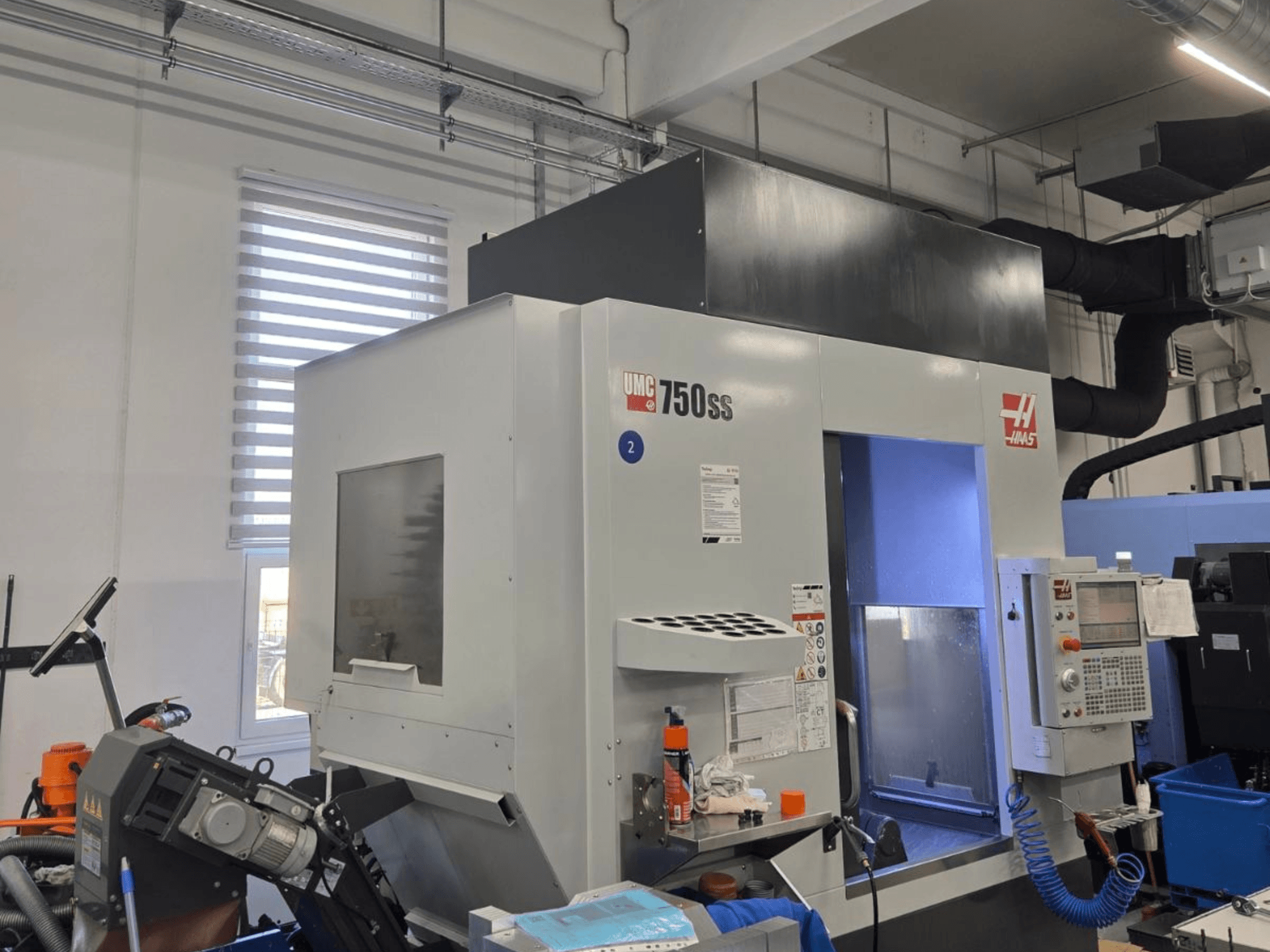 Вертикальный обрабатывающий центр Haas UMC-750SS, вид спереди, с панелью управления и свободным доступом к зоне обработки.