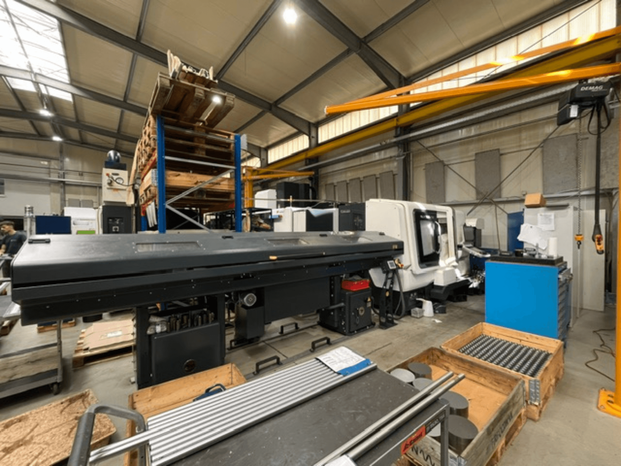 Горизонтальный токарный станок DMG MORI MORI NLX 2500/700 SY в заводской комплектации, вид сбоку, на фотографии видны инструменты и палеты.