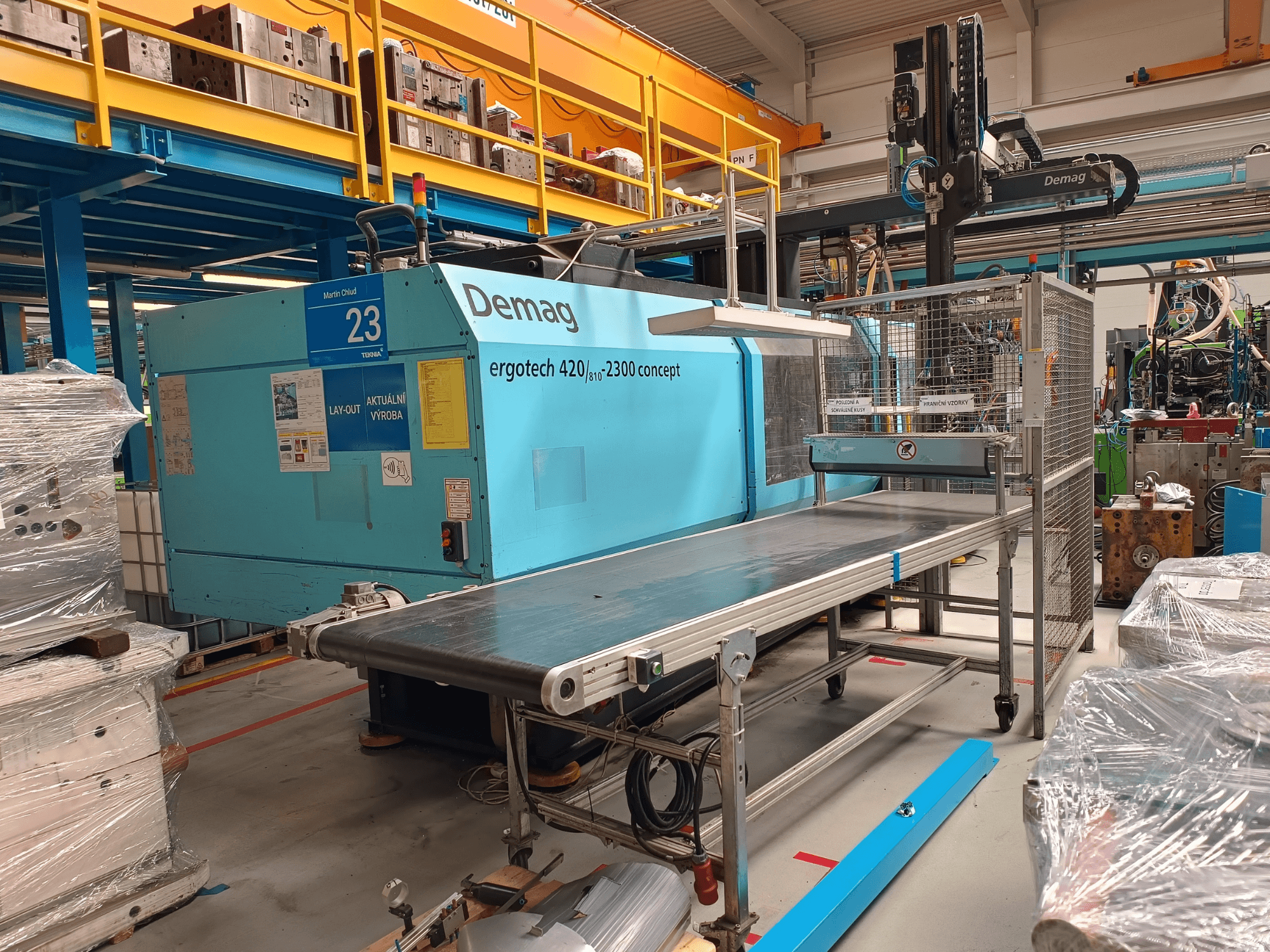Гидравлическая машина для литья под давлением Demag ergotech 420/810 - 2300 с конвейером и защитным кожухом в боковом разрезе.