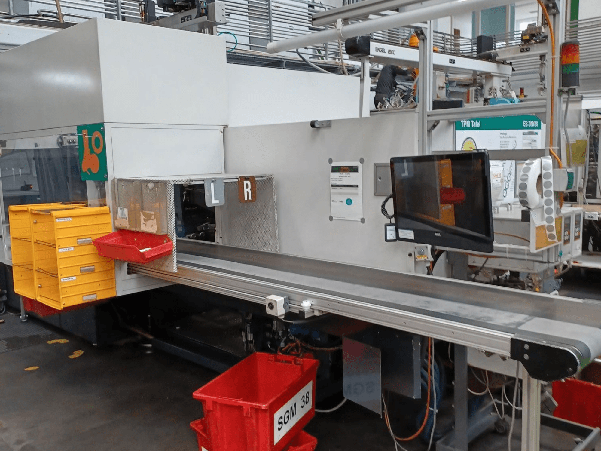 Промышленная сортировочная машина с желтыми и красными контейнерами, вид сбоку, с монитором управления и маркированными отделениями для сортировки.