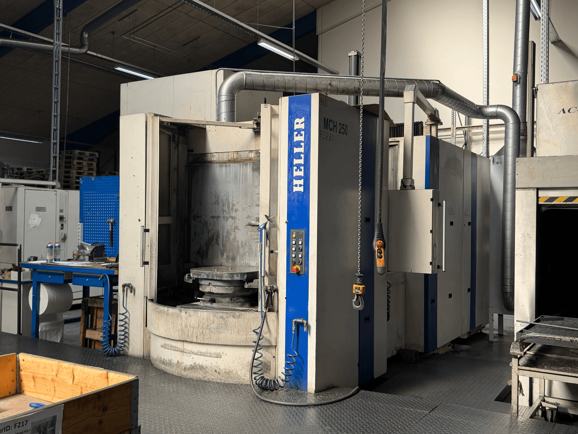 Вид спереди на горизонтальный обрабатывающий центр HELLER MCH 250 с панелью управления, большим вращающимся столом и промышленным окружением.