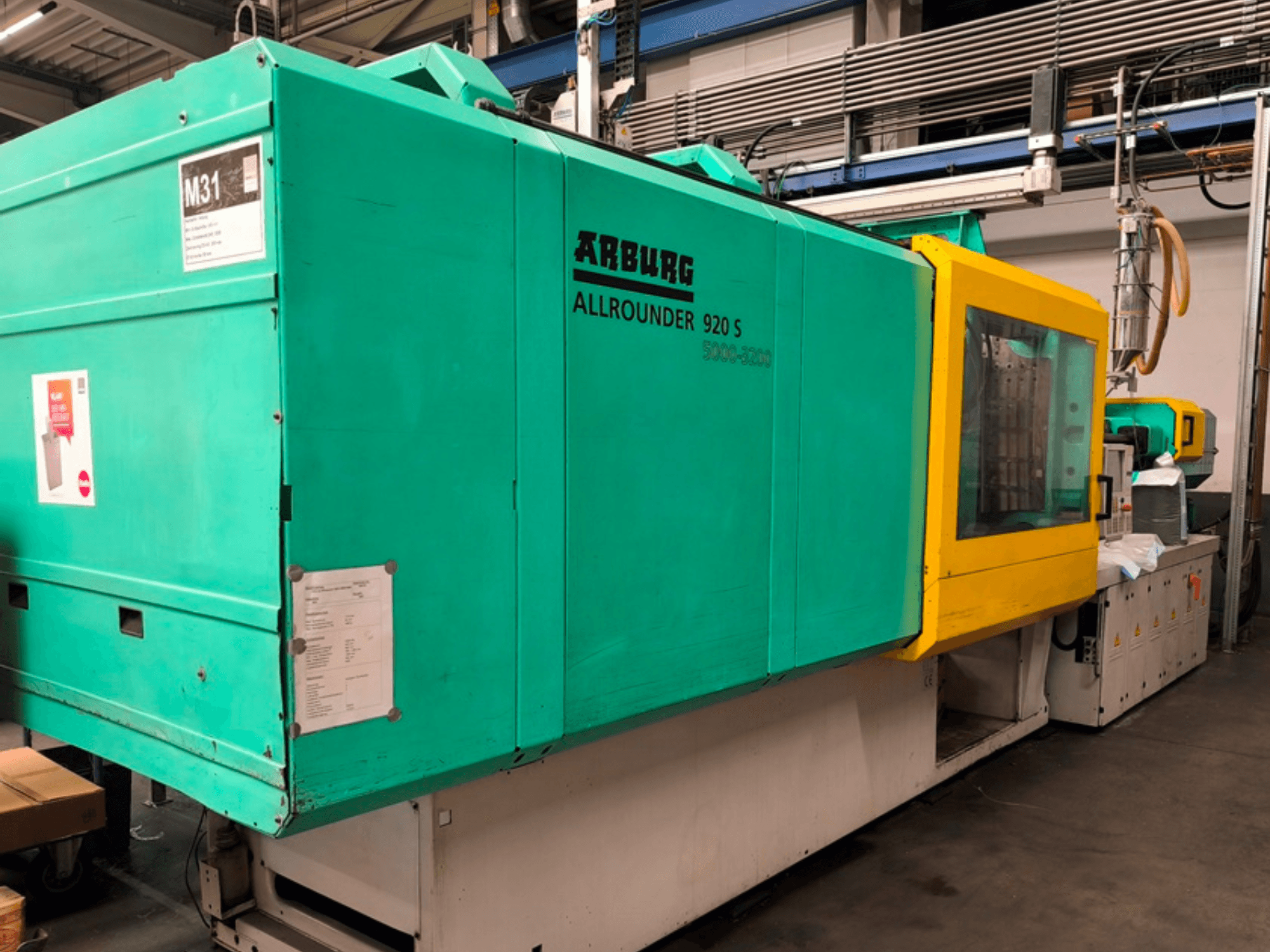 Термопластавтомат Arburg Allrounder 920 S в аква-синем и желтом цвете, вид сбоку с изображением панели управления и компонентов.