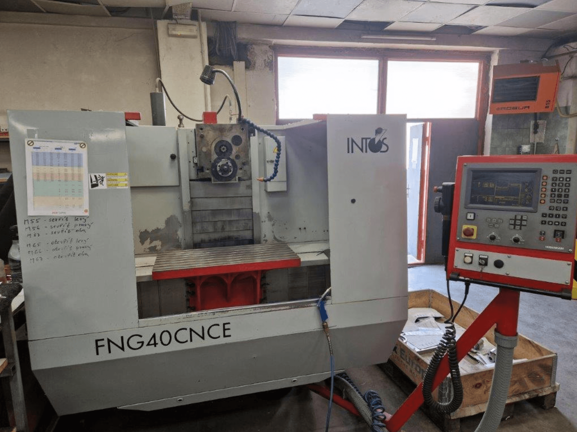 Станок INTOS FNG40CNC, вид спереди, имеет панель управления, рабочие части и металлический рабочий стол. Идеально подходит для обработки.