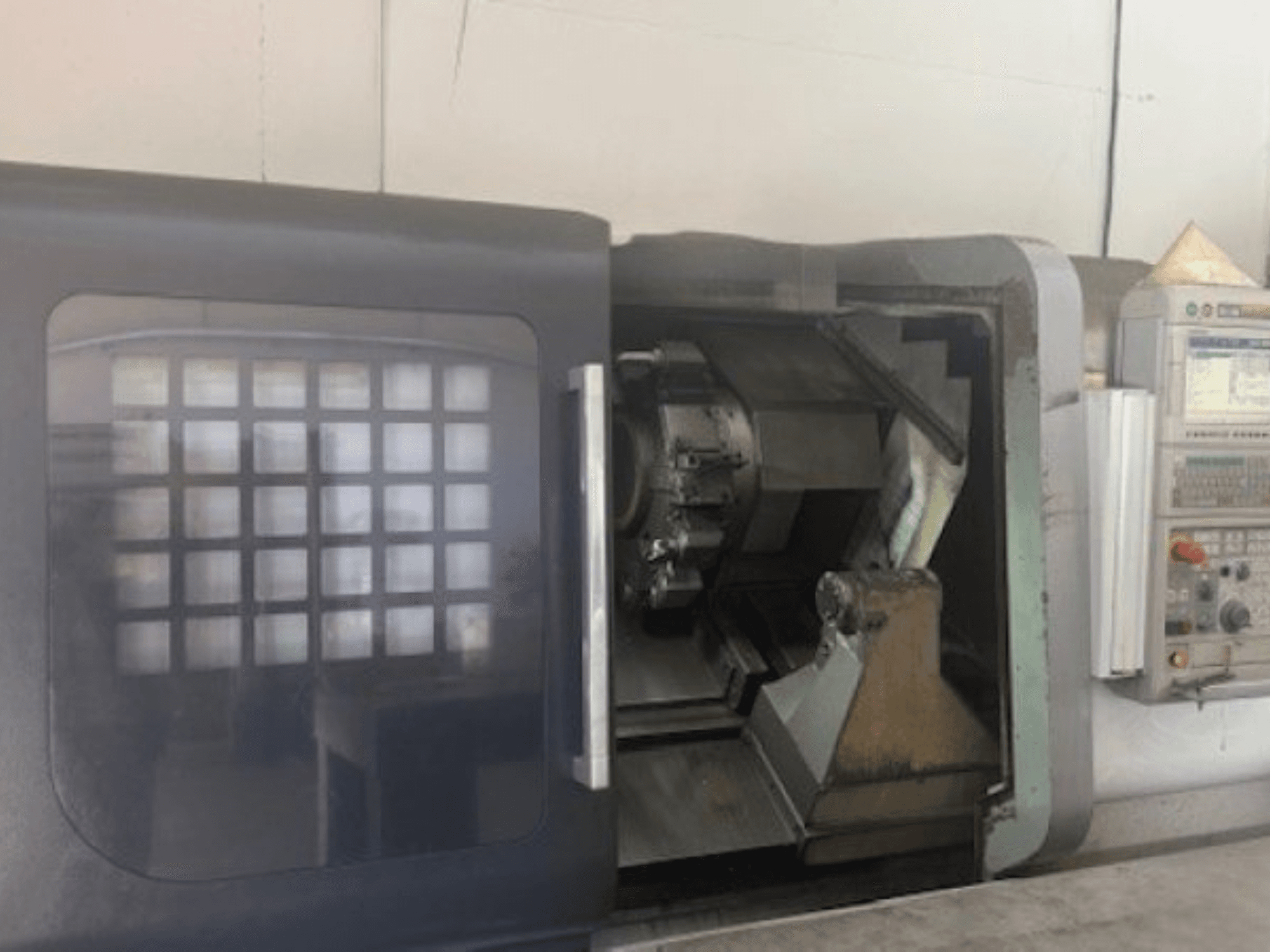 Горизонтальный токарный станок MORI SEIKI NLX 2500M, вид спереди, показывающий держатель инструмента, панель управления и внутренний механизм.