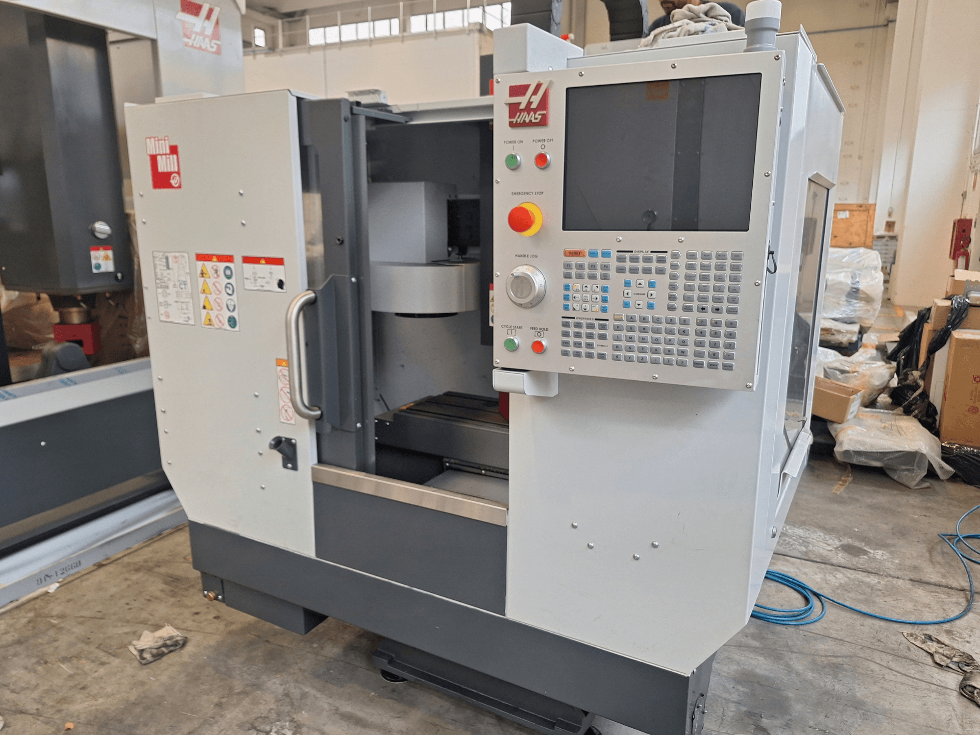 Вертикальный обрабатывающий центр HAAS Mini Mill, вид спереди, с панелью управления, оснащенной кнопками и дисплеем.