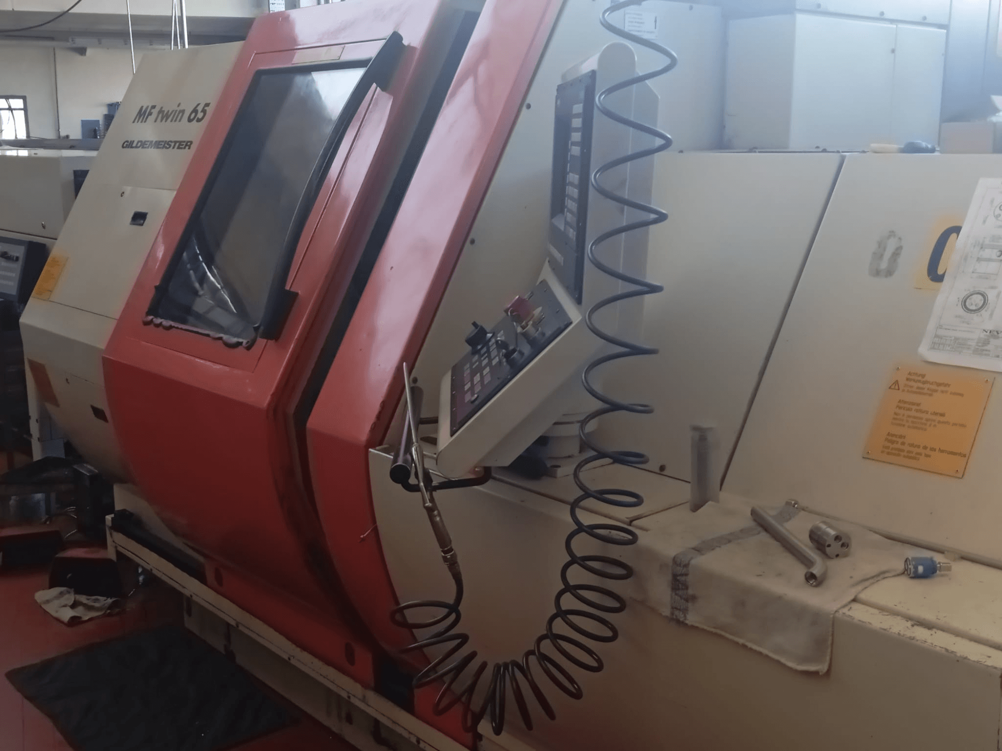 Оранжево-белая машина MF twin 65 Gliedemeister, вид спереди, с изображением панели управления и инструментов на ткани.