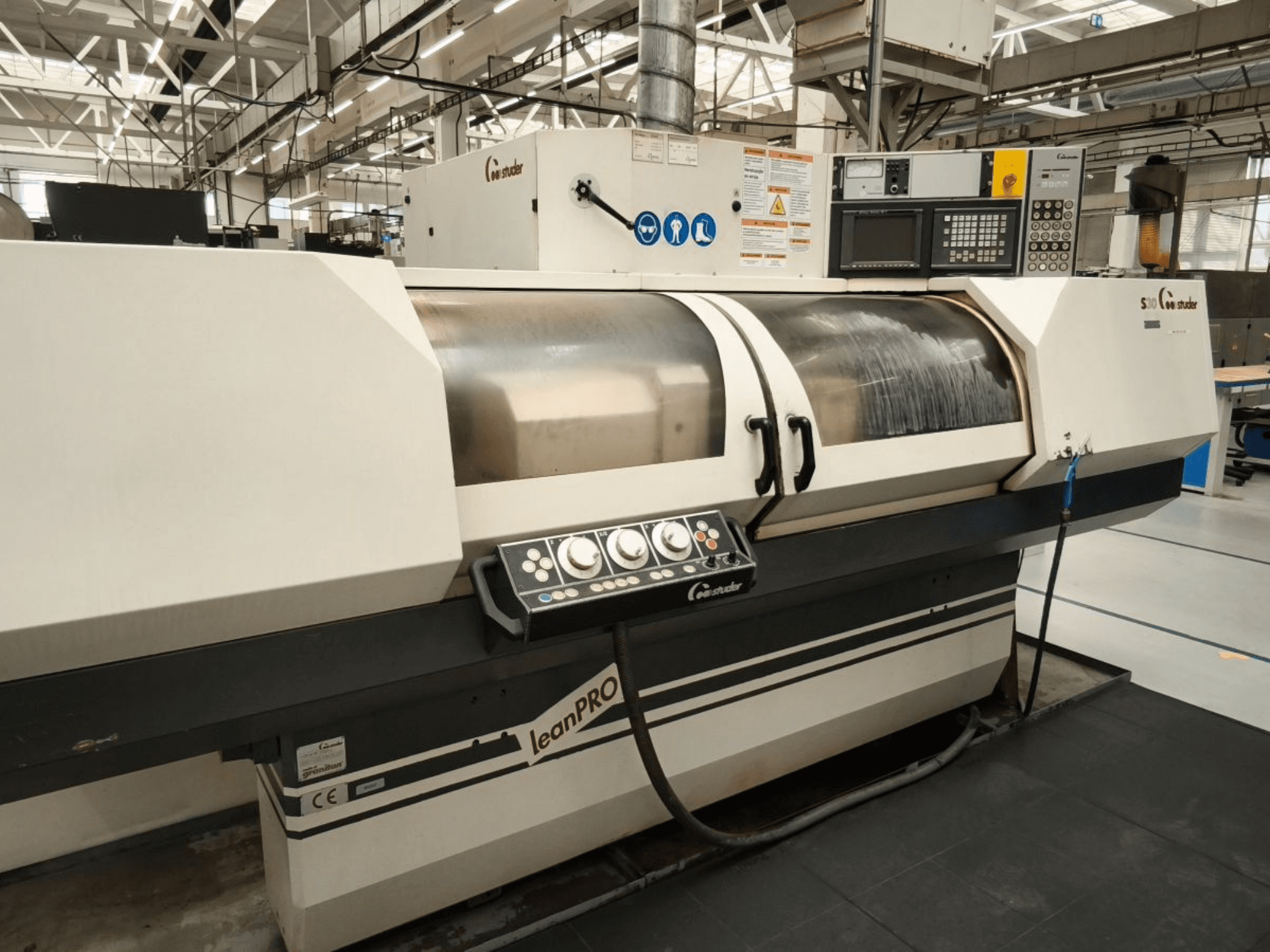 Круглошлифовальный станок STUDER S30 LEAN PRO, вид сбоку, демонстрирует панель управления и крышку шлифовального круга в промышленной обстановке.