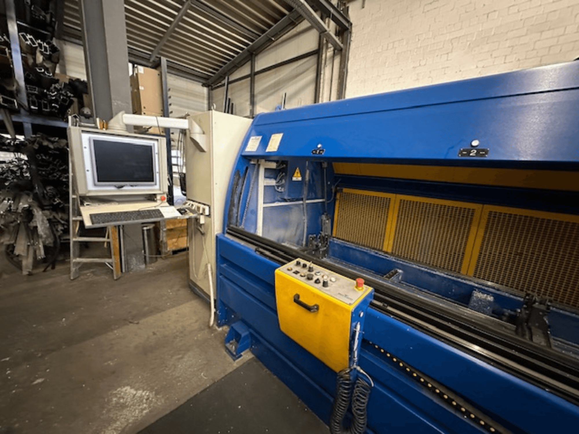 Вид спереди на SCHÜCO Profilbearbeitungscenter 299 650, универсальный обрабатывающий центр с органами управления и компьютерной рабочей станцией.